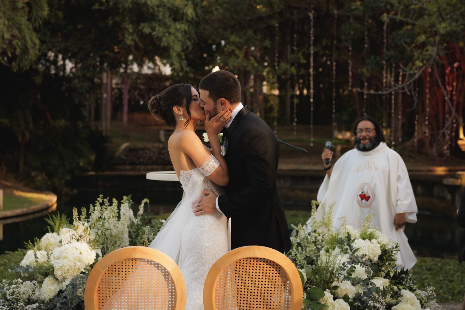 Romantic garden wedding scene with elegant white floral arrangements and natural greenery backdrop.