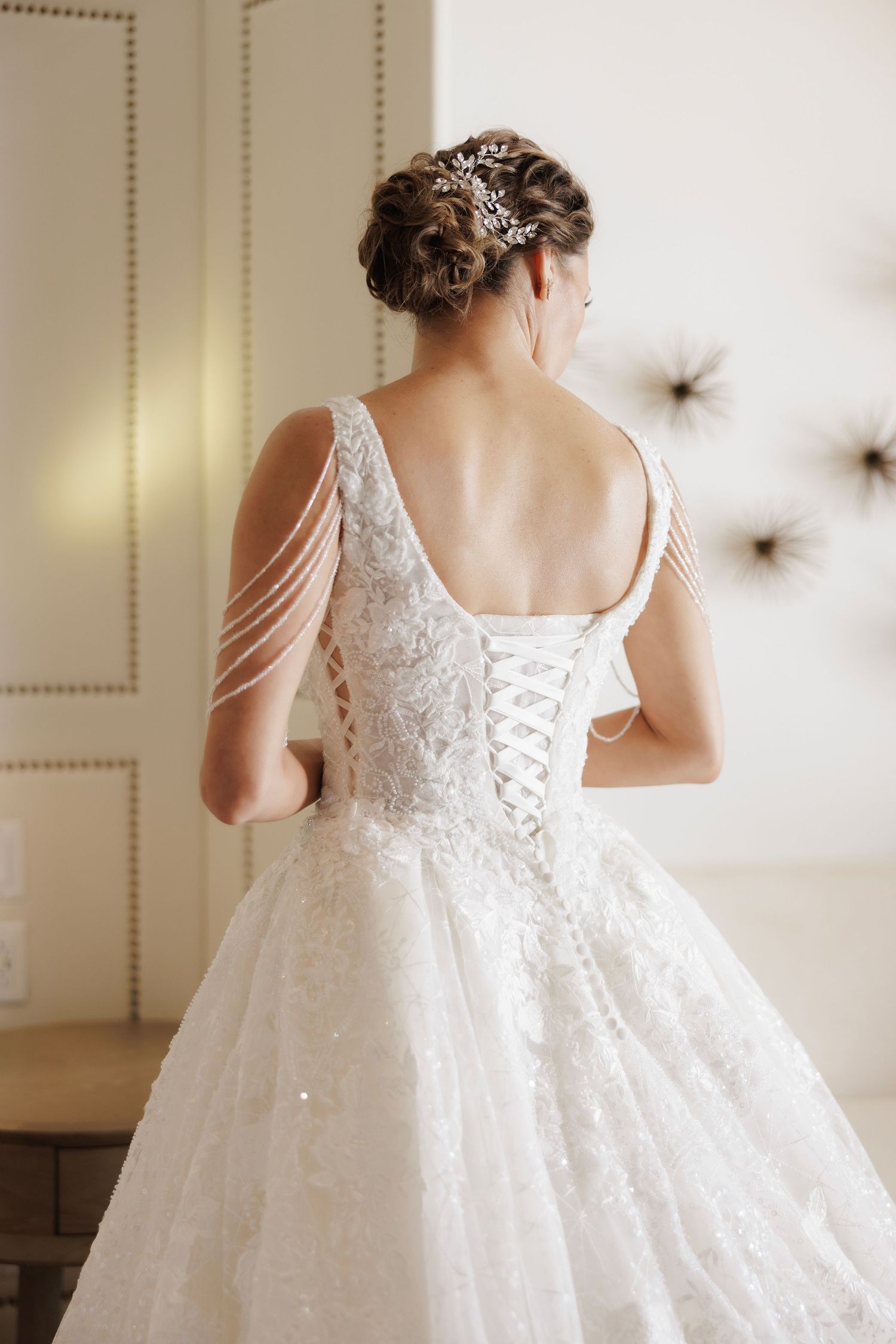 A delicate white wedding dress with intricate lace details and corset back is displayed in multiple angles.