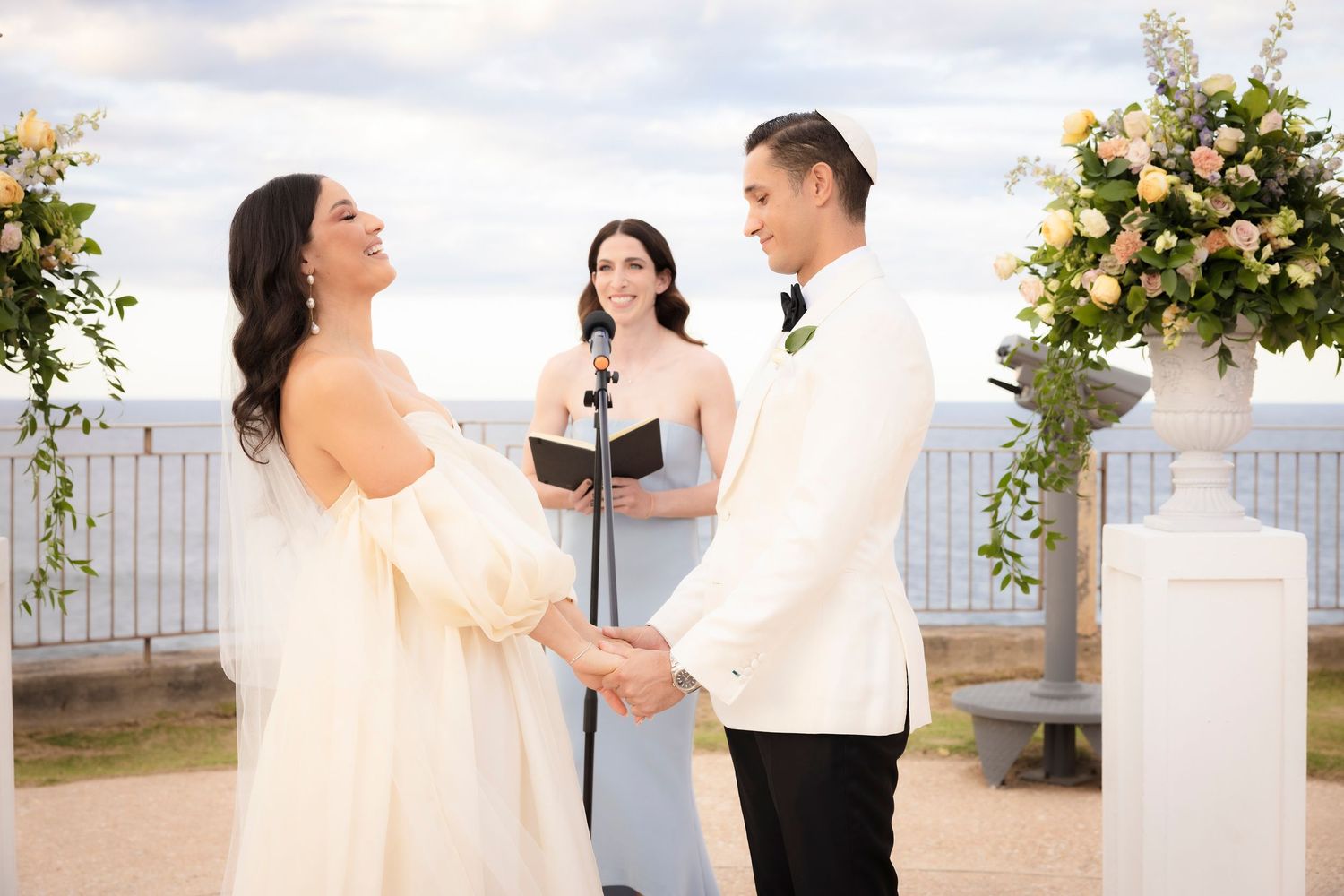 An elegant outdoor wedding ceremony setup with floral arrangements and white columns.