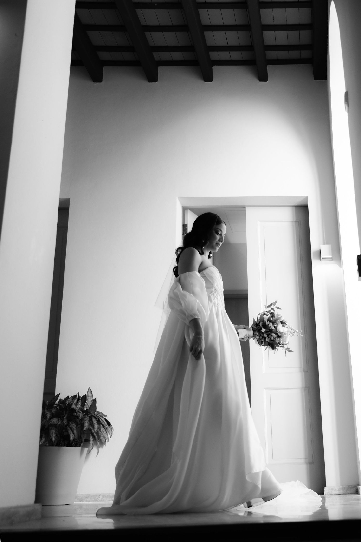 Silhouette of a wedding dress flowing in a bright white interior with dramatic columns.
