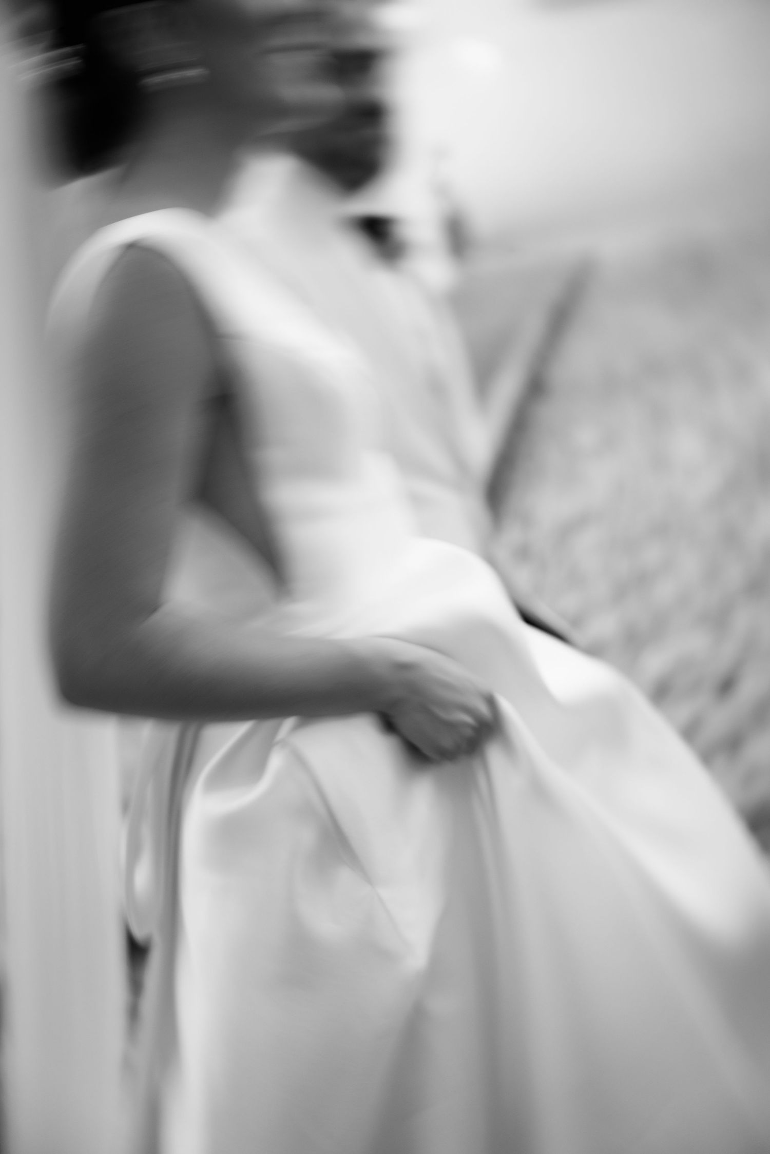 Artistic black and white close-up of a flowing white wedding dress fabric being held.
