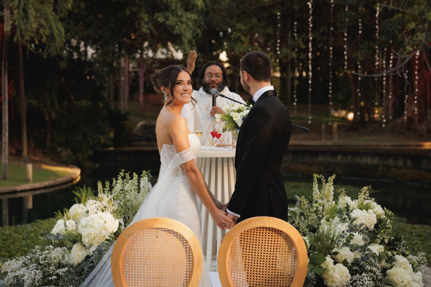 A couple having a romantic outdoor reception moment in a rustic garden setting with string lights and floral decor.