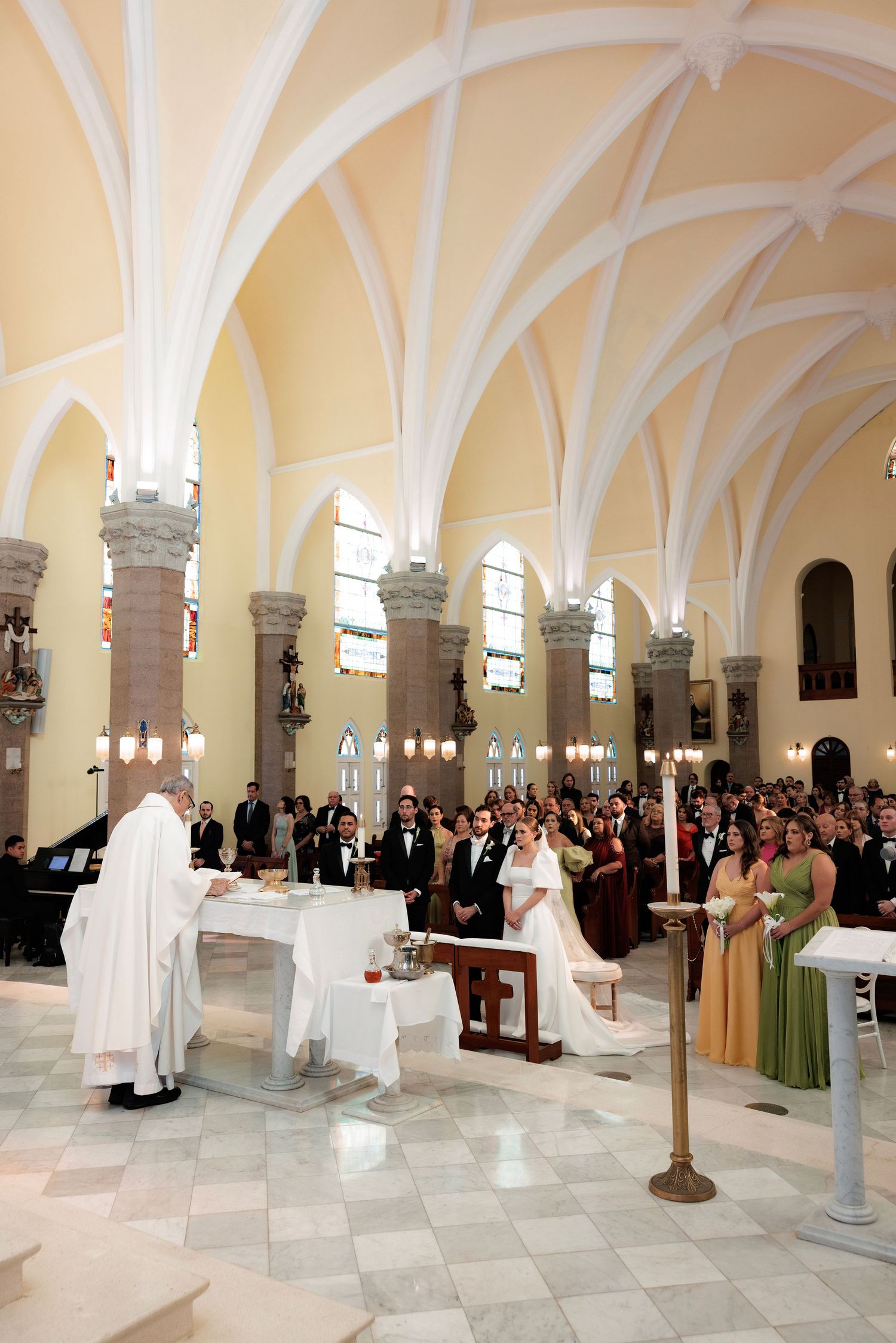 A panoramic view of a church interior with arched vaults and columns during a formal ceremony with gathered attendees.