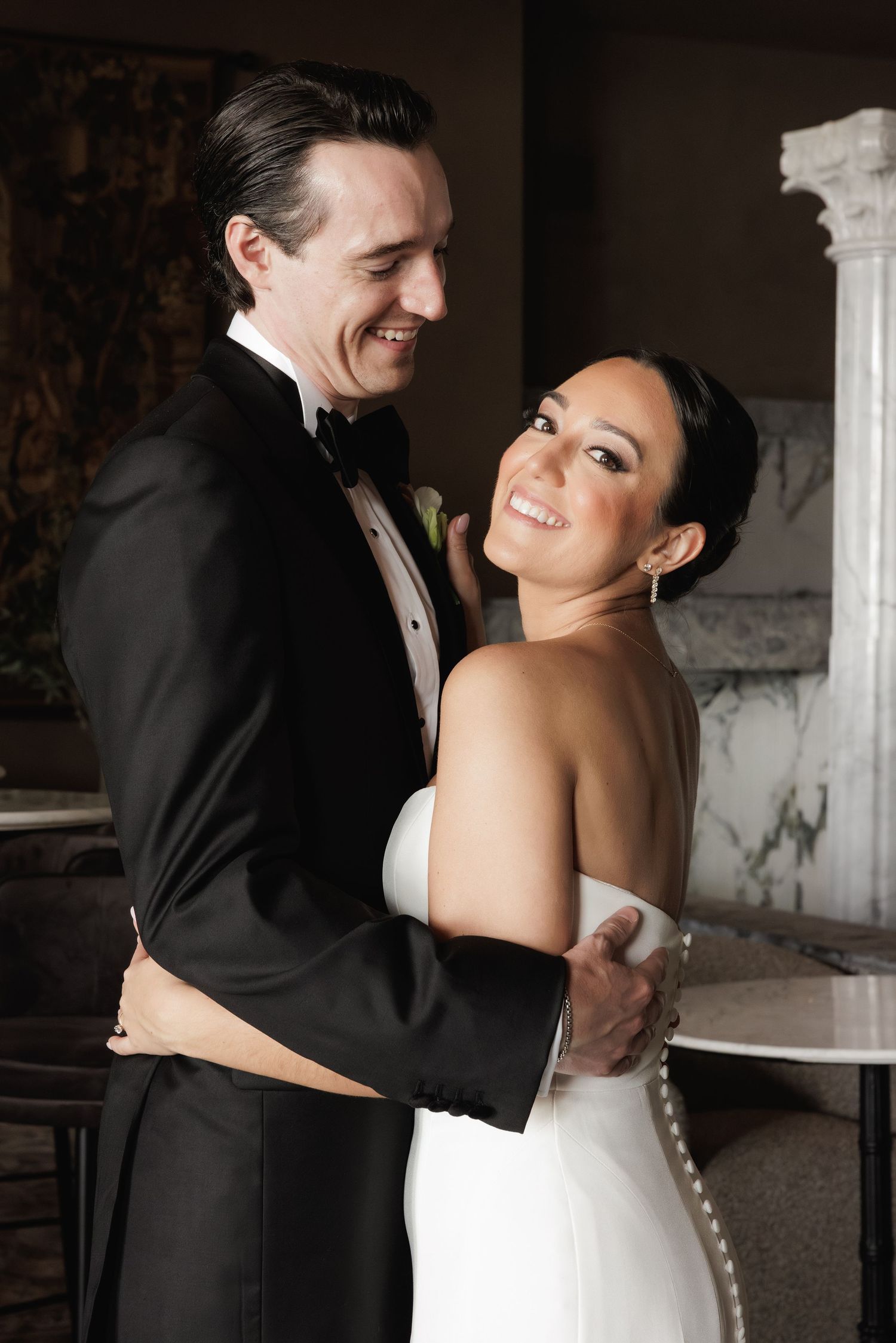 A bride and groom share romantic dance moves together in black and white formal wedding attire.
