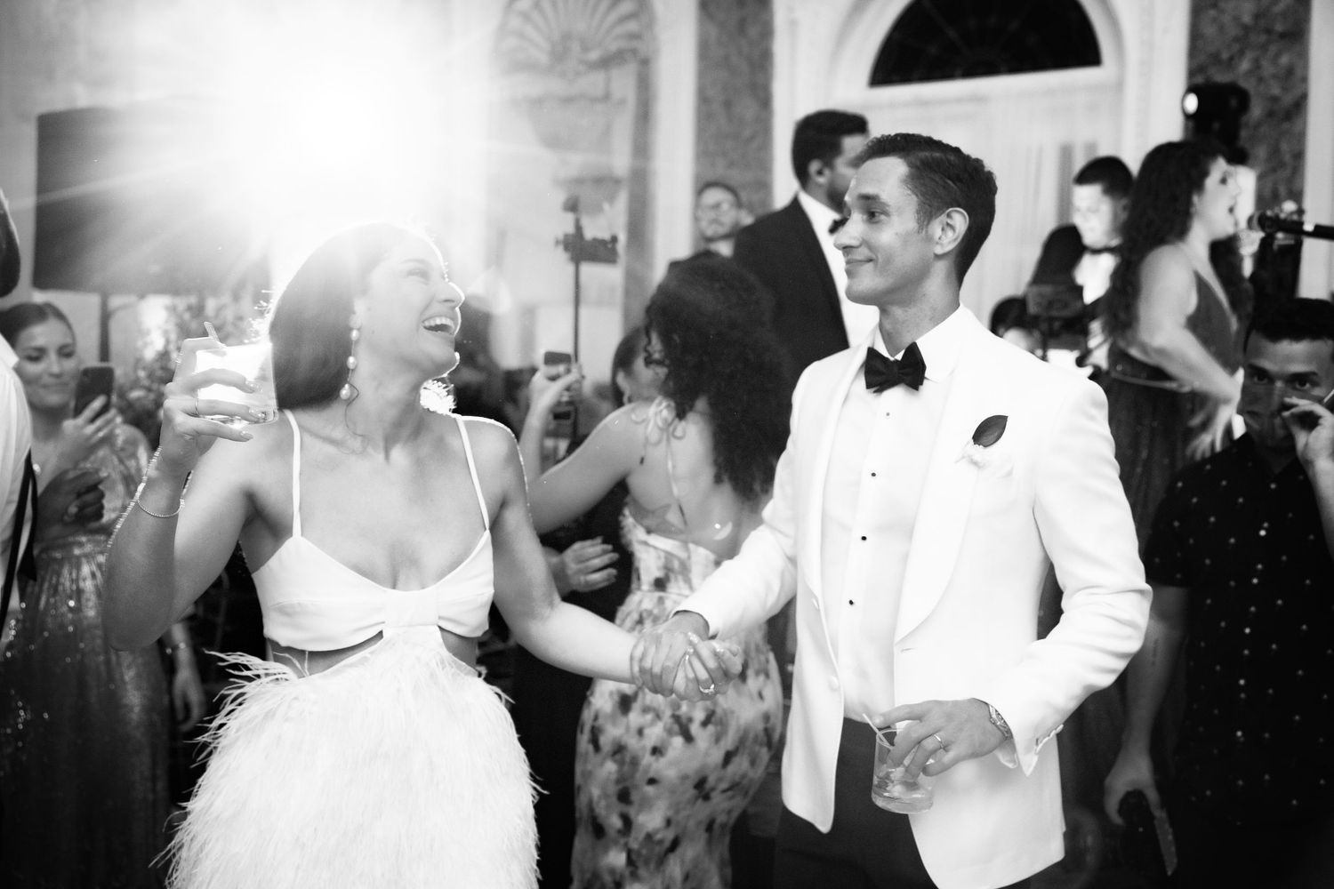 Black and white photo of formal event guests mingling and dancing at an elegant reception.