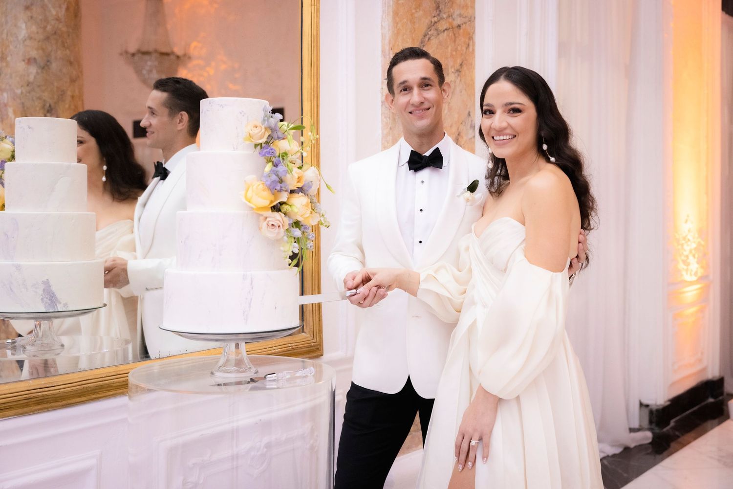 Elegant wedding celebration with couples dancing under crystal chandeliers in a luxurious white ballroom.
