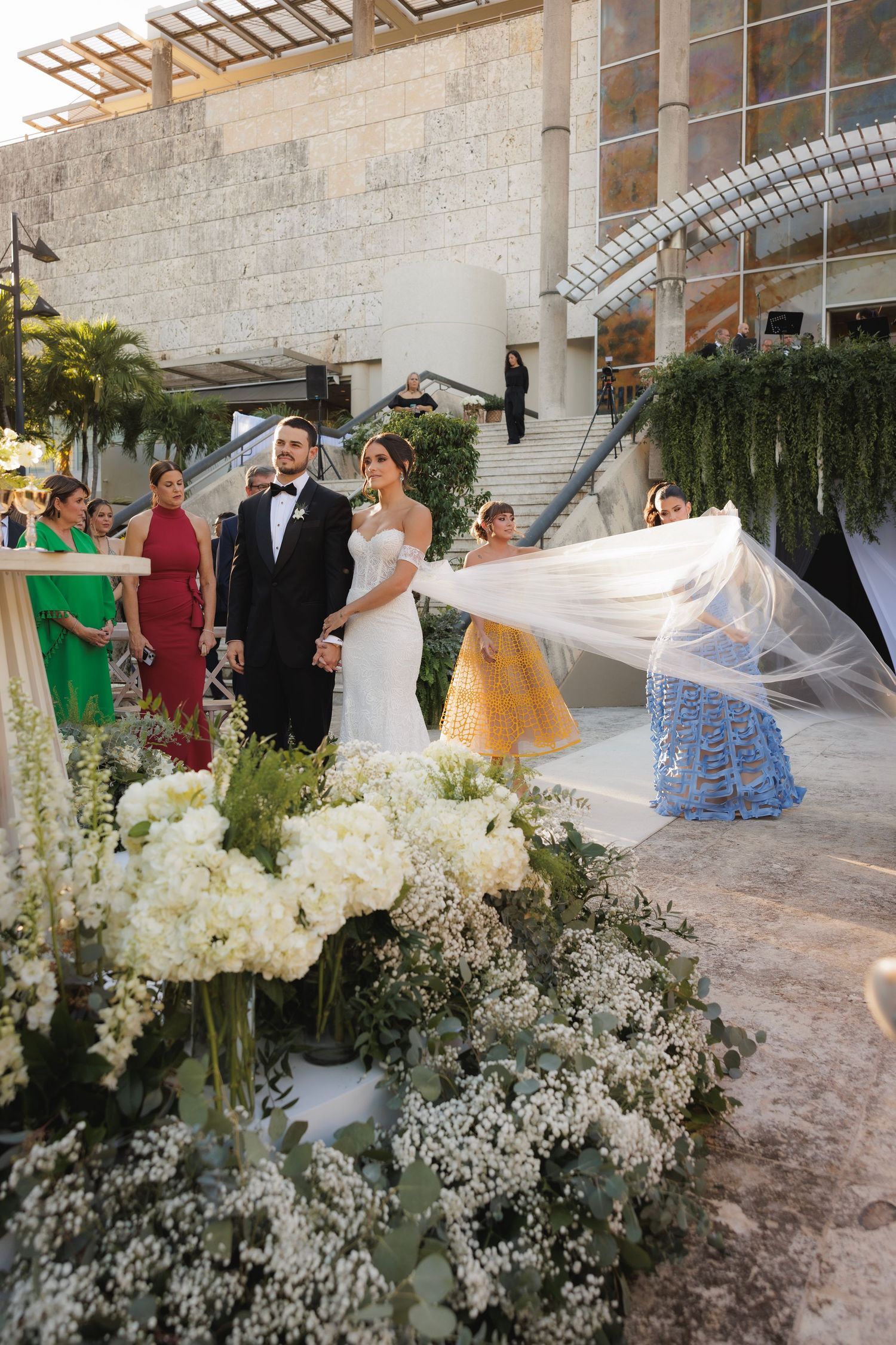 Group arrangements at an elegant wedding venue with abundant white floral decorations and stone architecture.