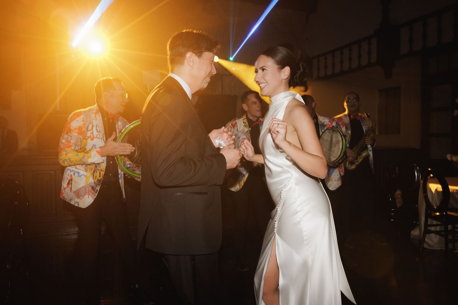 Newlyweds dance together under dramatic golden lighting at their reception.