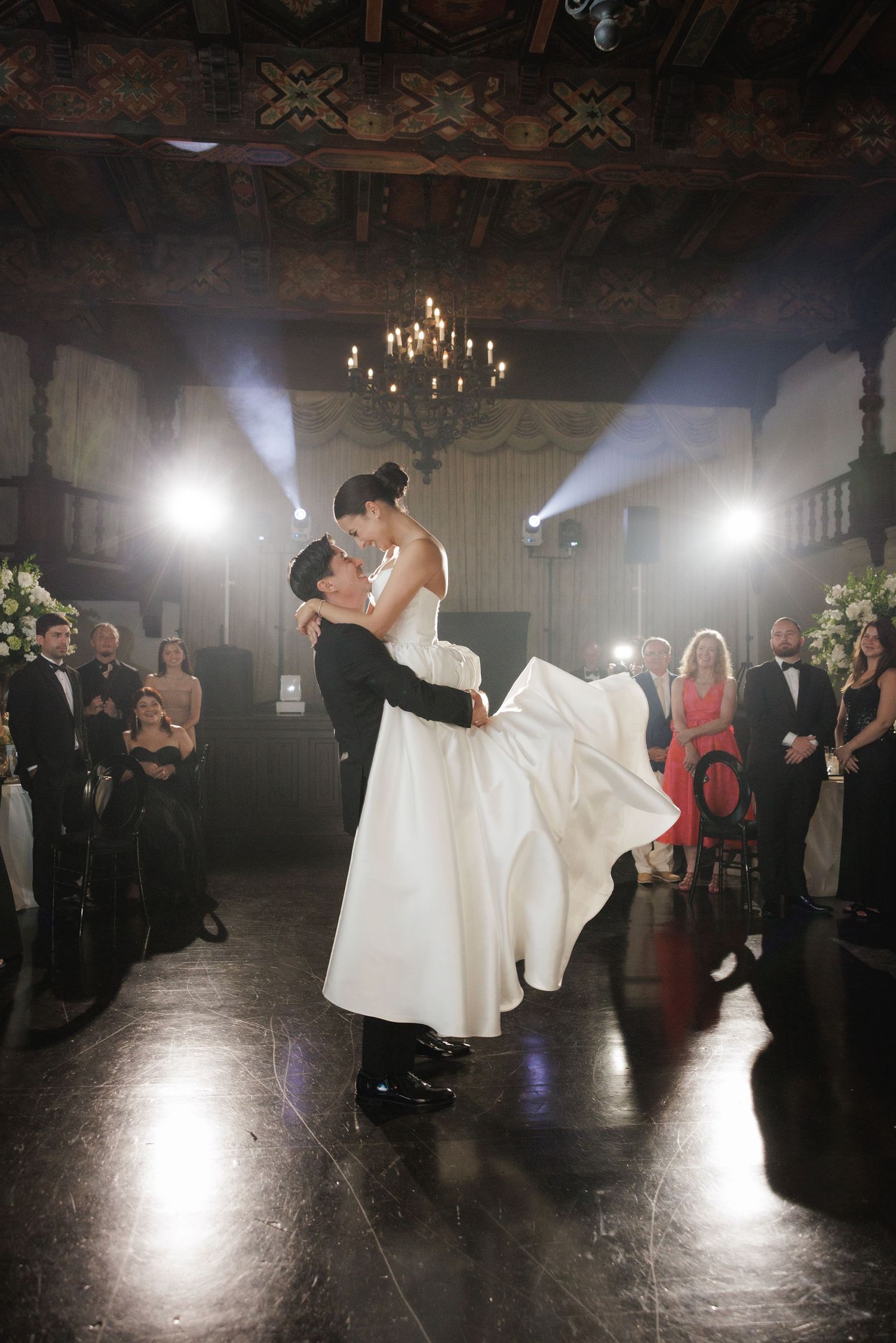 Dramatic first dance sequence captured in a dimly lit ballroom with spotlights.