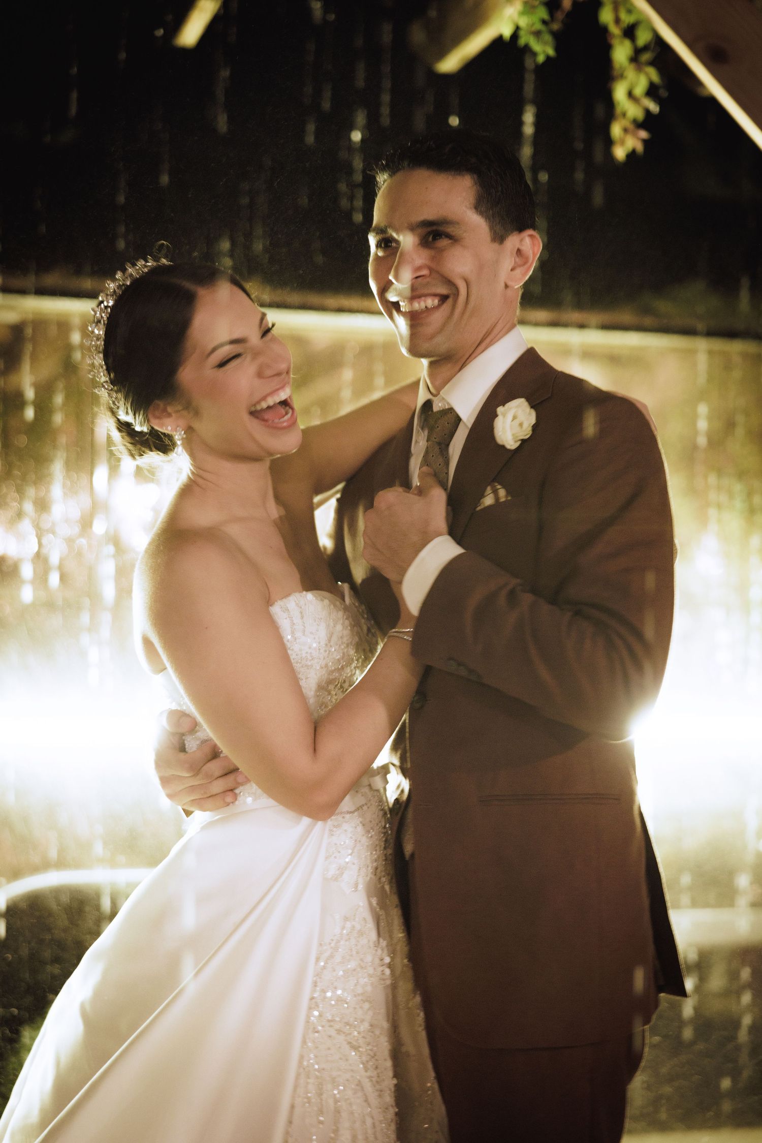 A romantic wedding couple shares an intimate moment while dancing together in warm evening lighting.