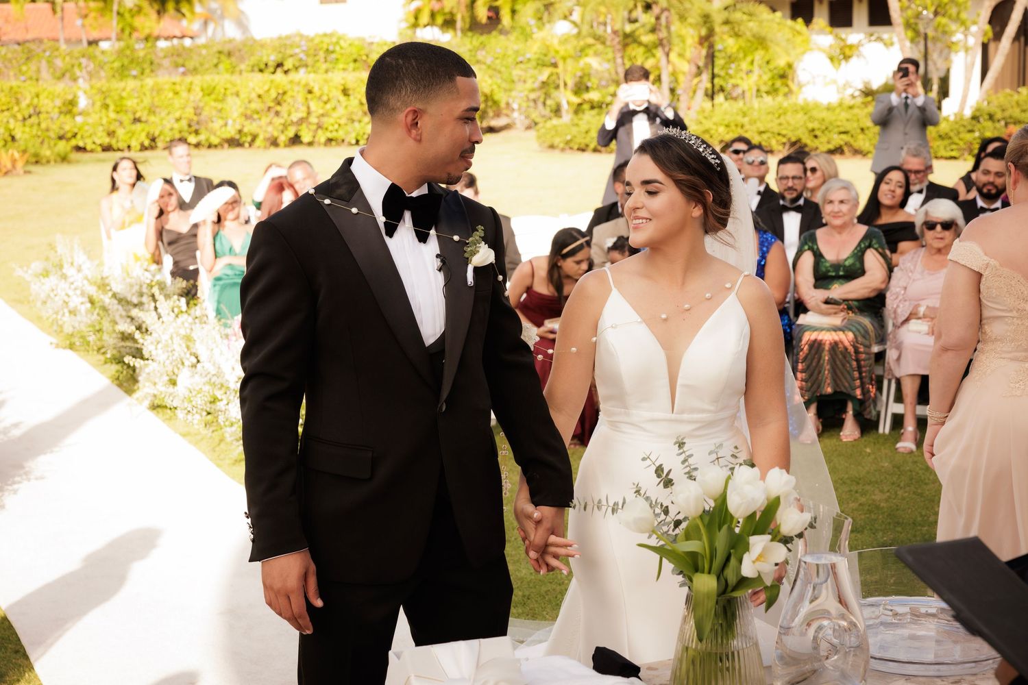 A bride and groom share a special moment during their outdoor garden wedding ceremony with guests in attendance.