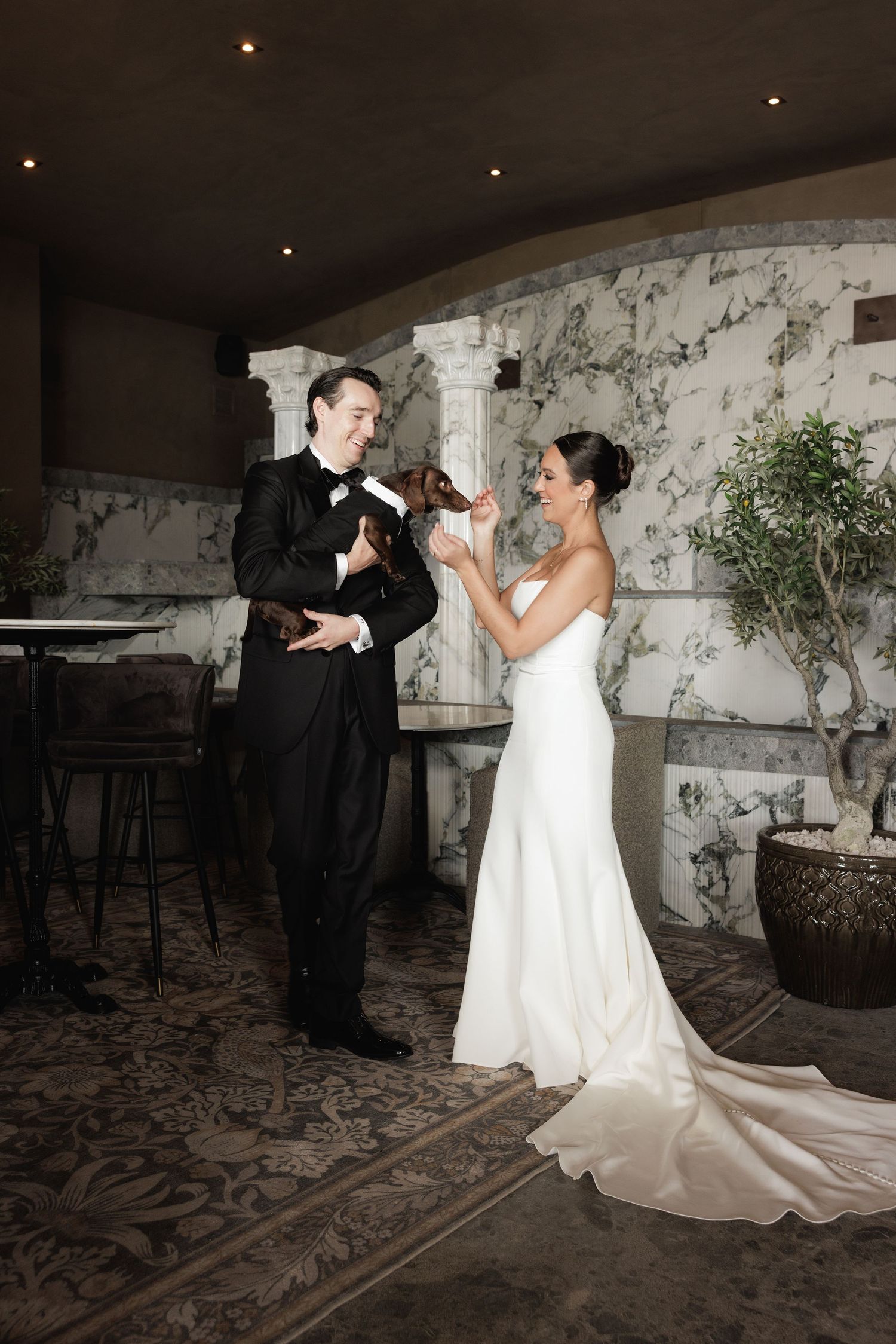 Bride and groom dance together in an elegant reception venue with marble walls and carpeted floors.
