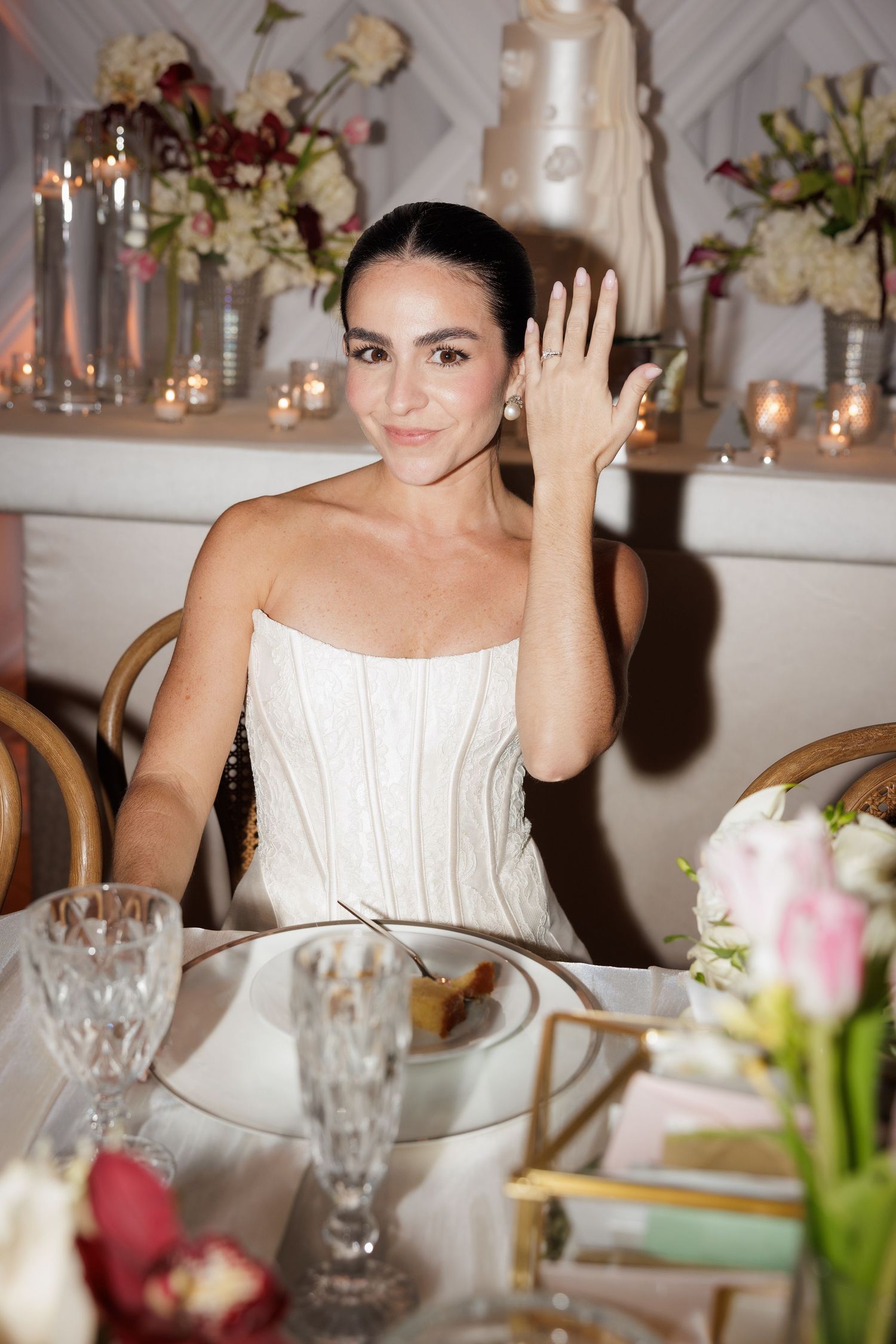 Wedding reception scene with elegant table settings, floral centerpieces, and guests enjoying the celebration.