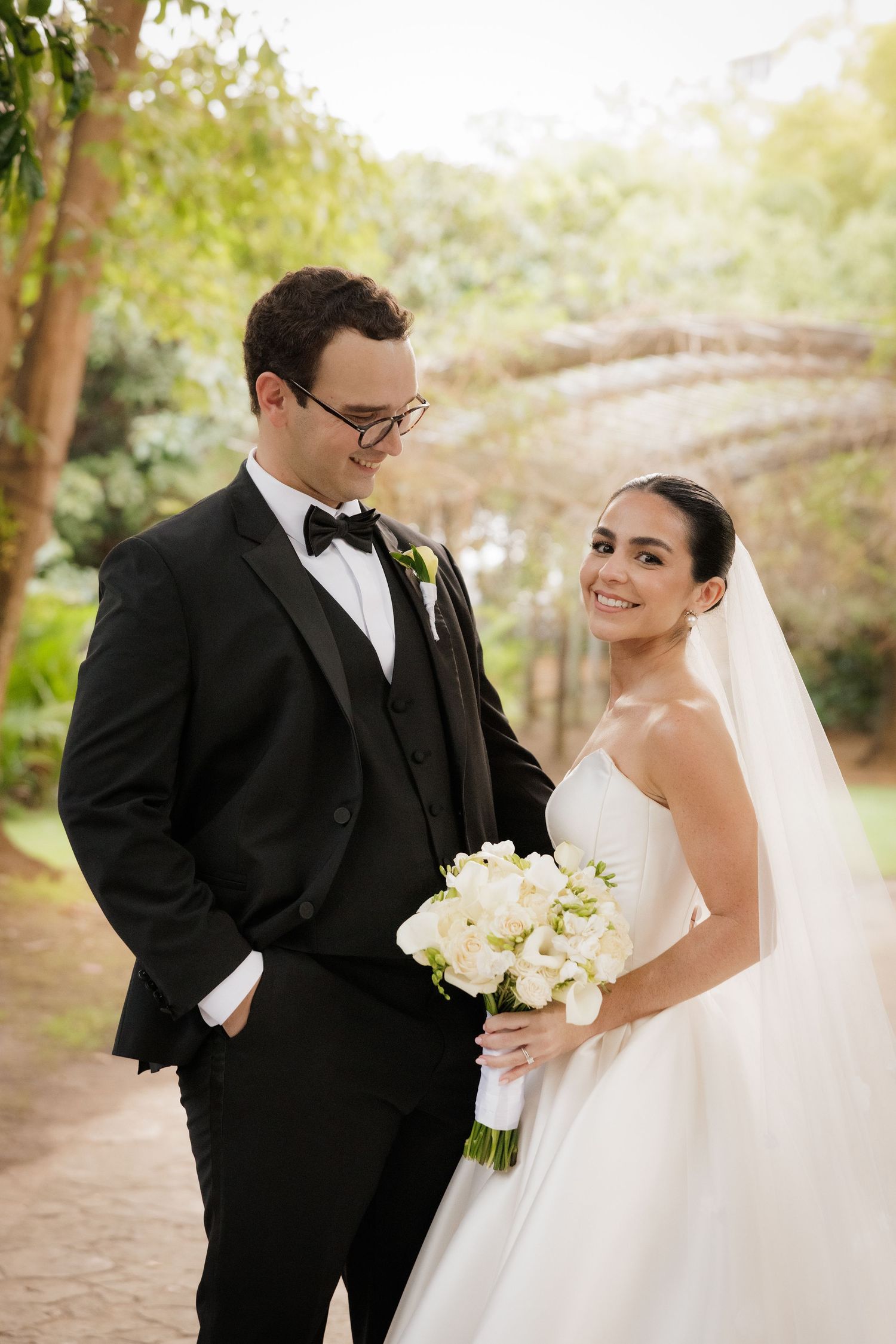 A romantic outdoor wedding portrait with white bouquet and flowing bridal gown.