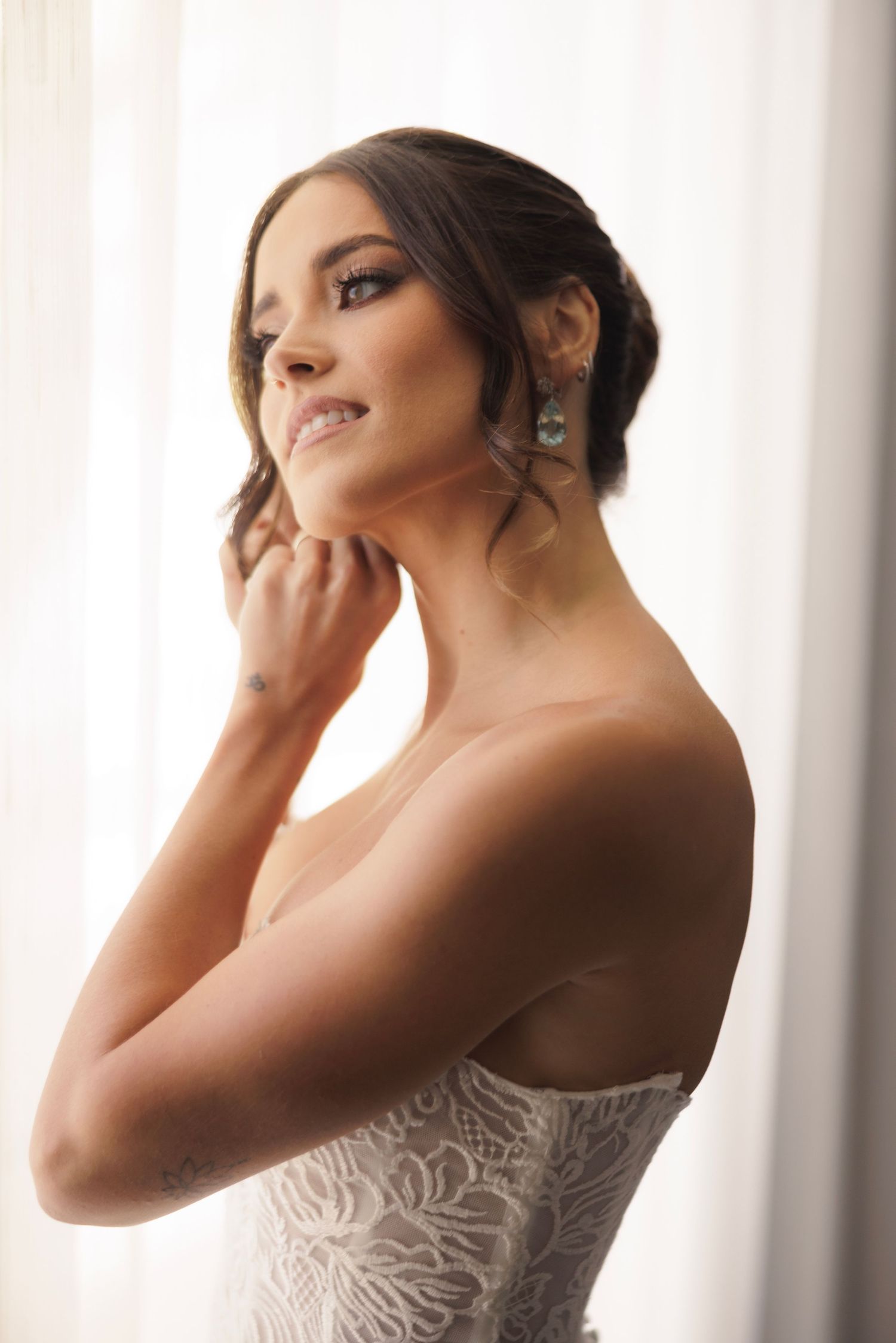Close up portrait of bride wearing strapless lace wedding dress and elegant updo hairstyle.