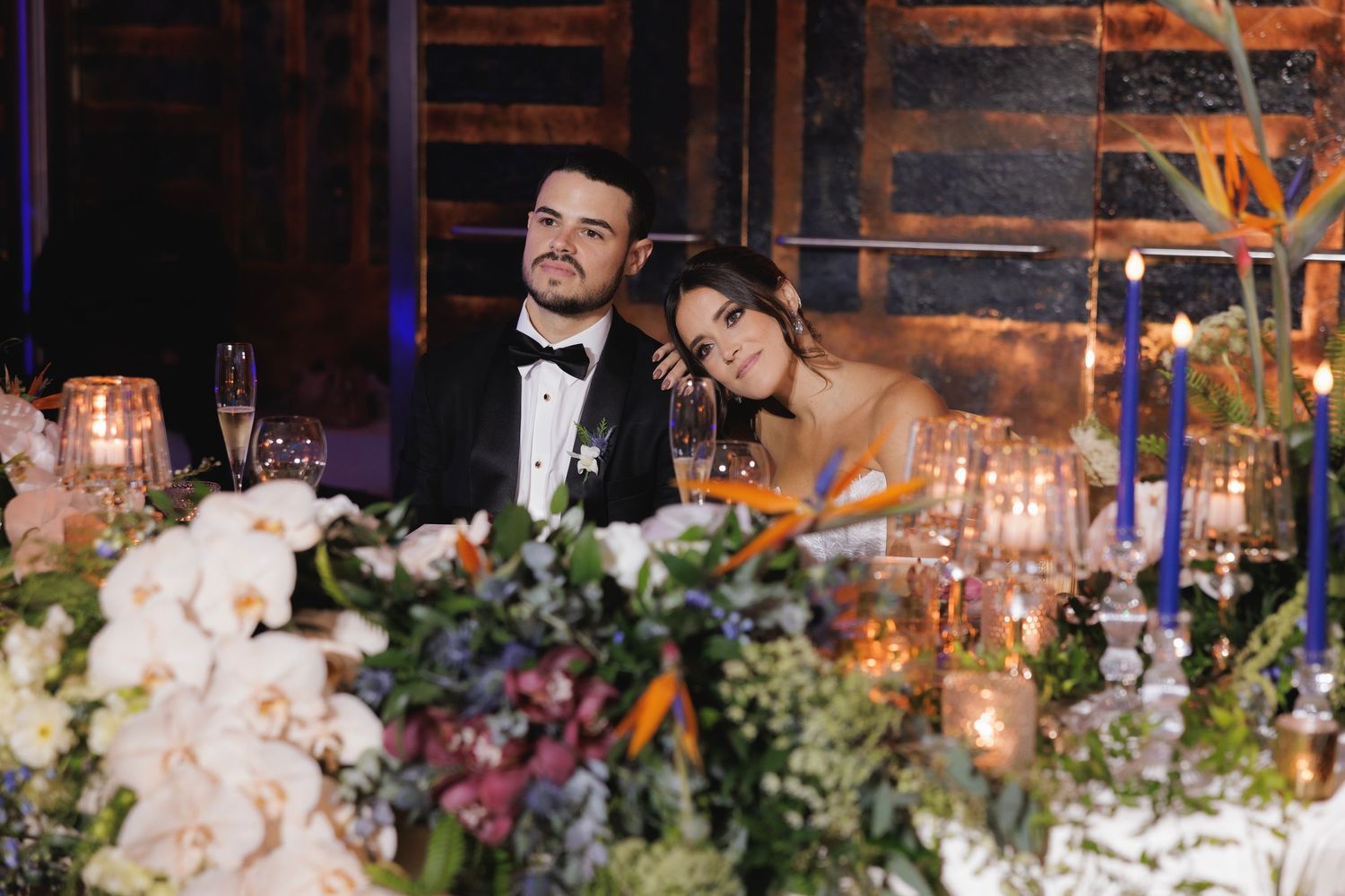 Romantic table setting at wedding reception with lush floral centerpieces and candlelight.