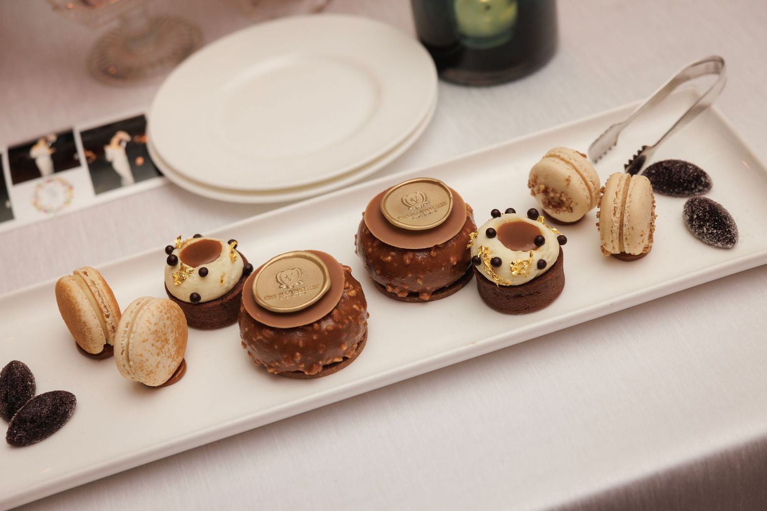 An elegant plate of chocolate desserts and macarons arranged on a white serving platter with decorative garnishes.