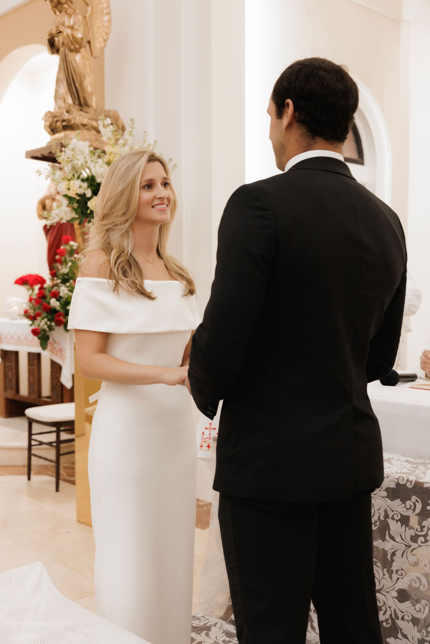 A couple shares a romantic first look moment in an elegantly decorated white room during their wedding ceremony.