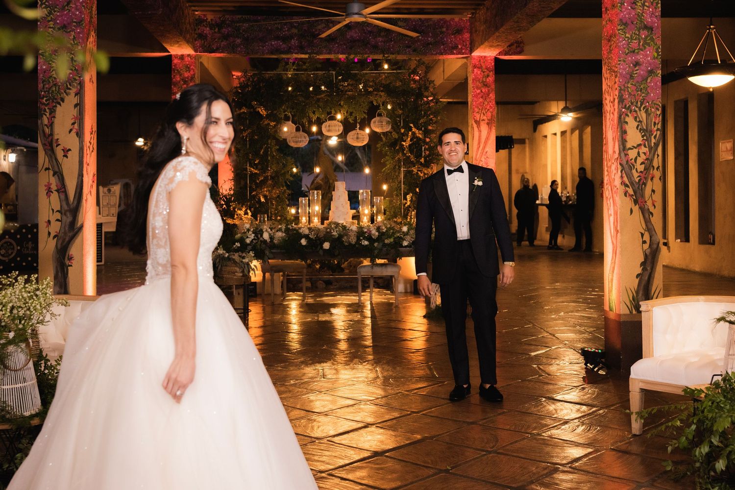 Romantic evening wedding reception scene with couple dancing under warm amber lighting.