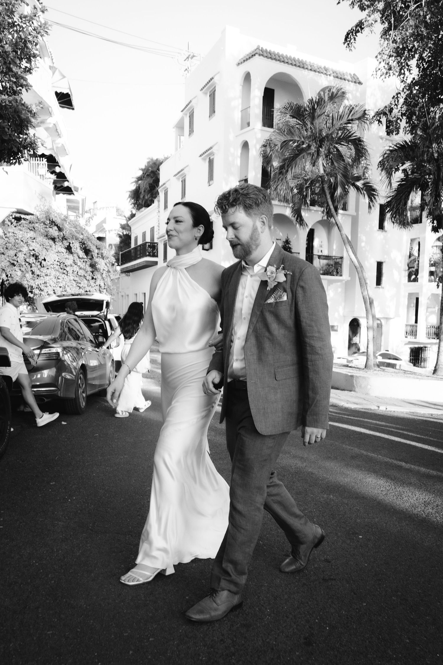 Wedding couple walking along a palm-lined street in black and white.