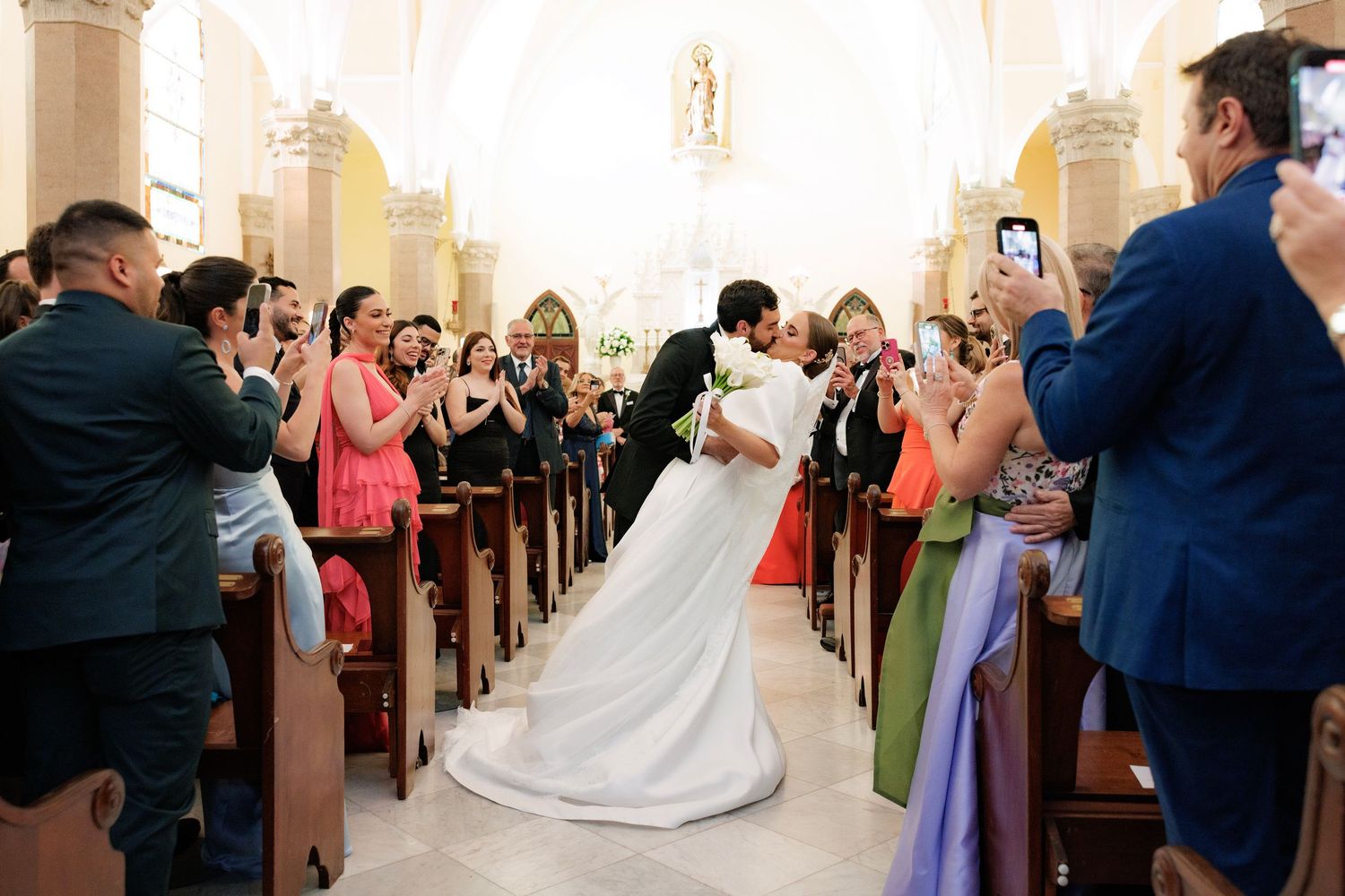 Couples dancing at a wedding reception in a dimly lit church sanctuary with wooden pews.