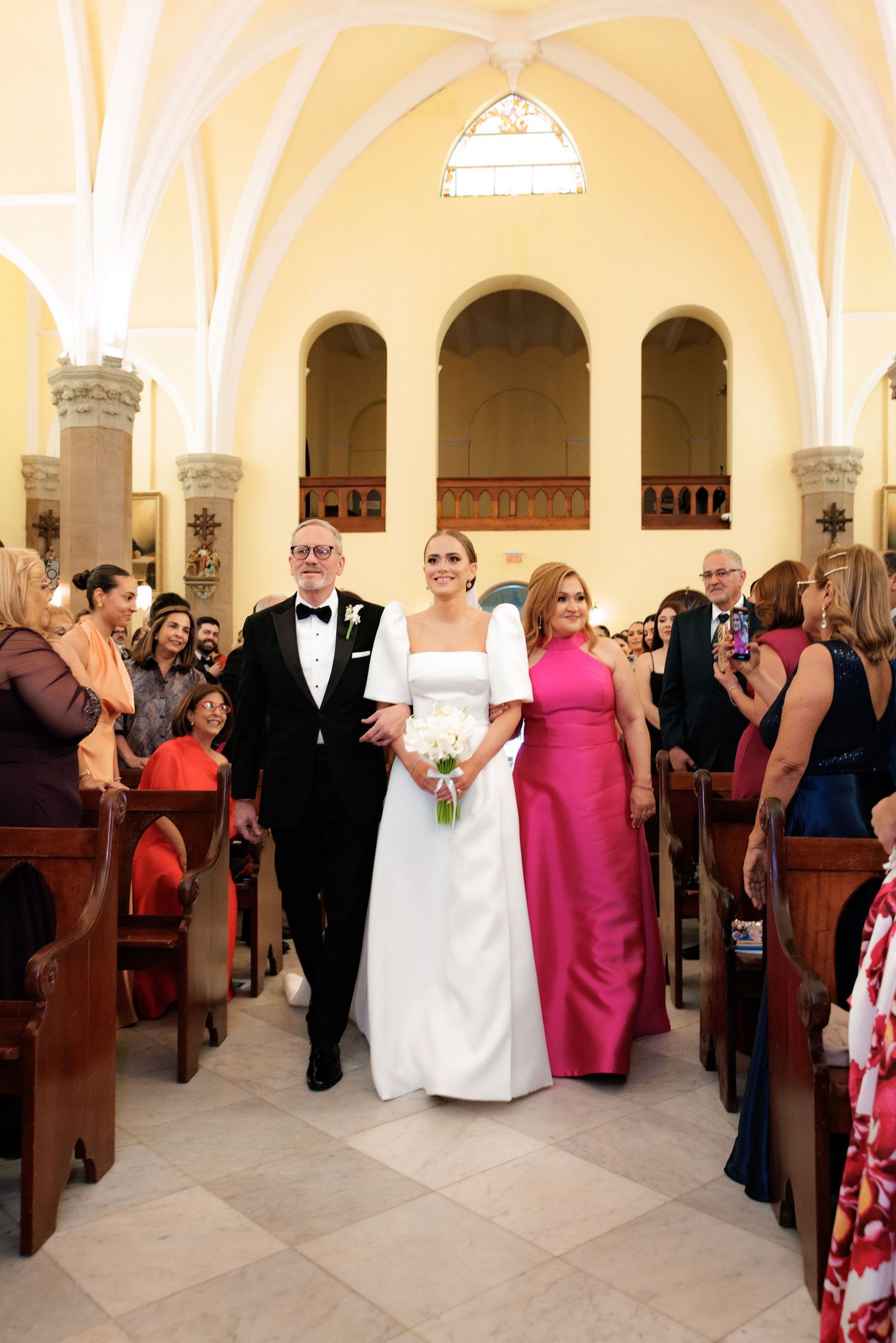 A panoramic view of a wedding ceremony in a church with vaulted ceilings and ornate architecture.
