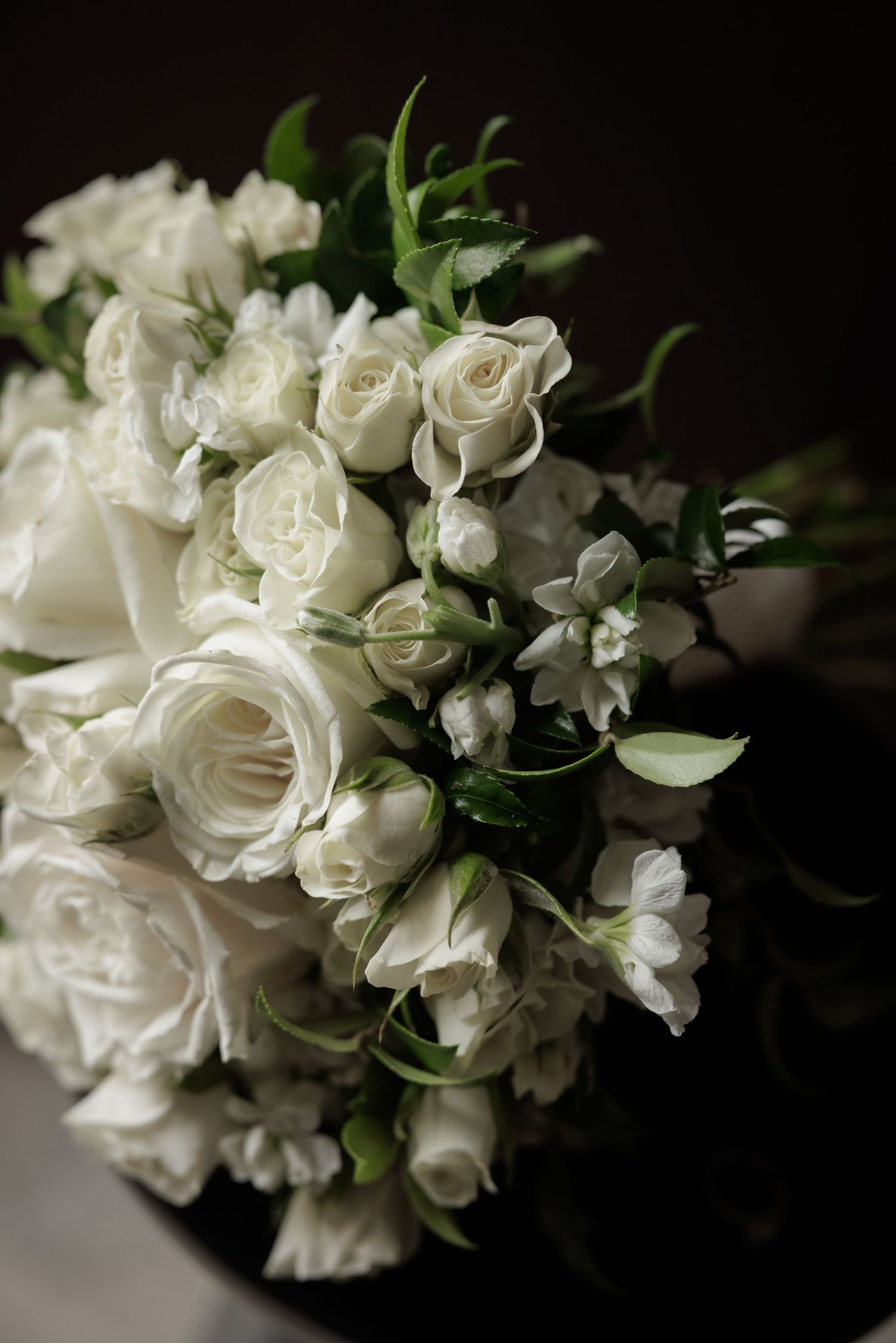 Elegant white roses and floral bouquet arrangement against dark background with soft focus.