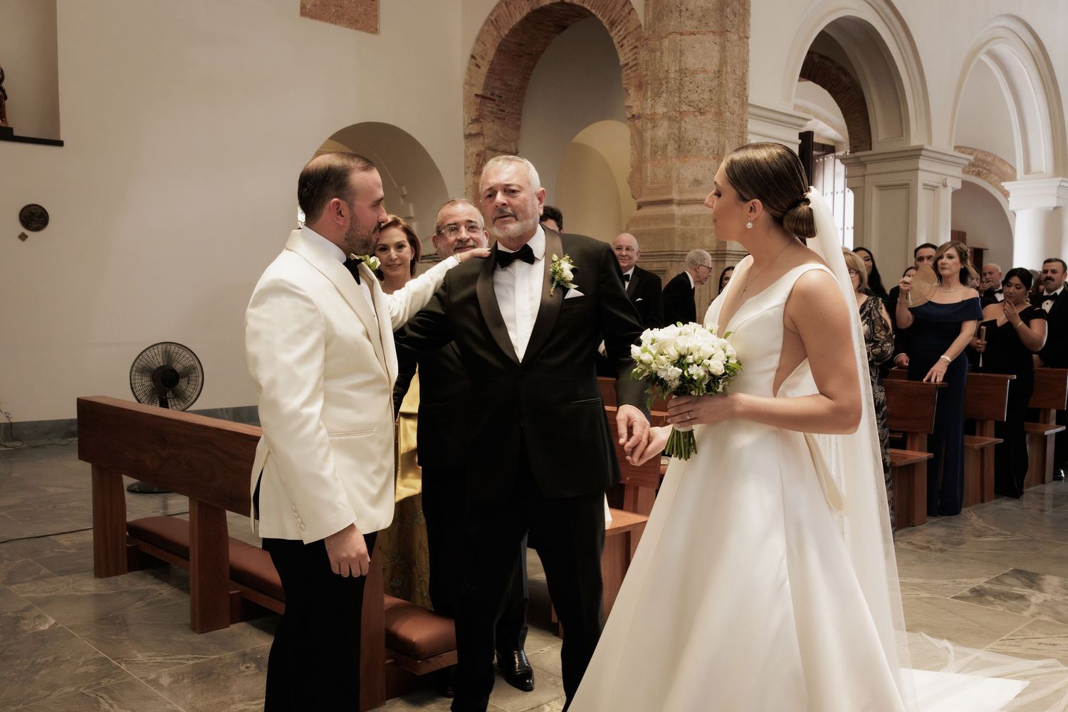 A wedding ceremony taking place inside a traditional stone church with vaulted arches and wooden pews.