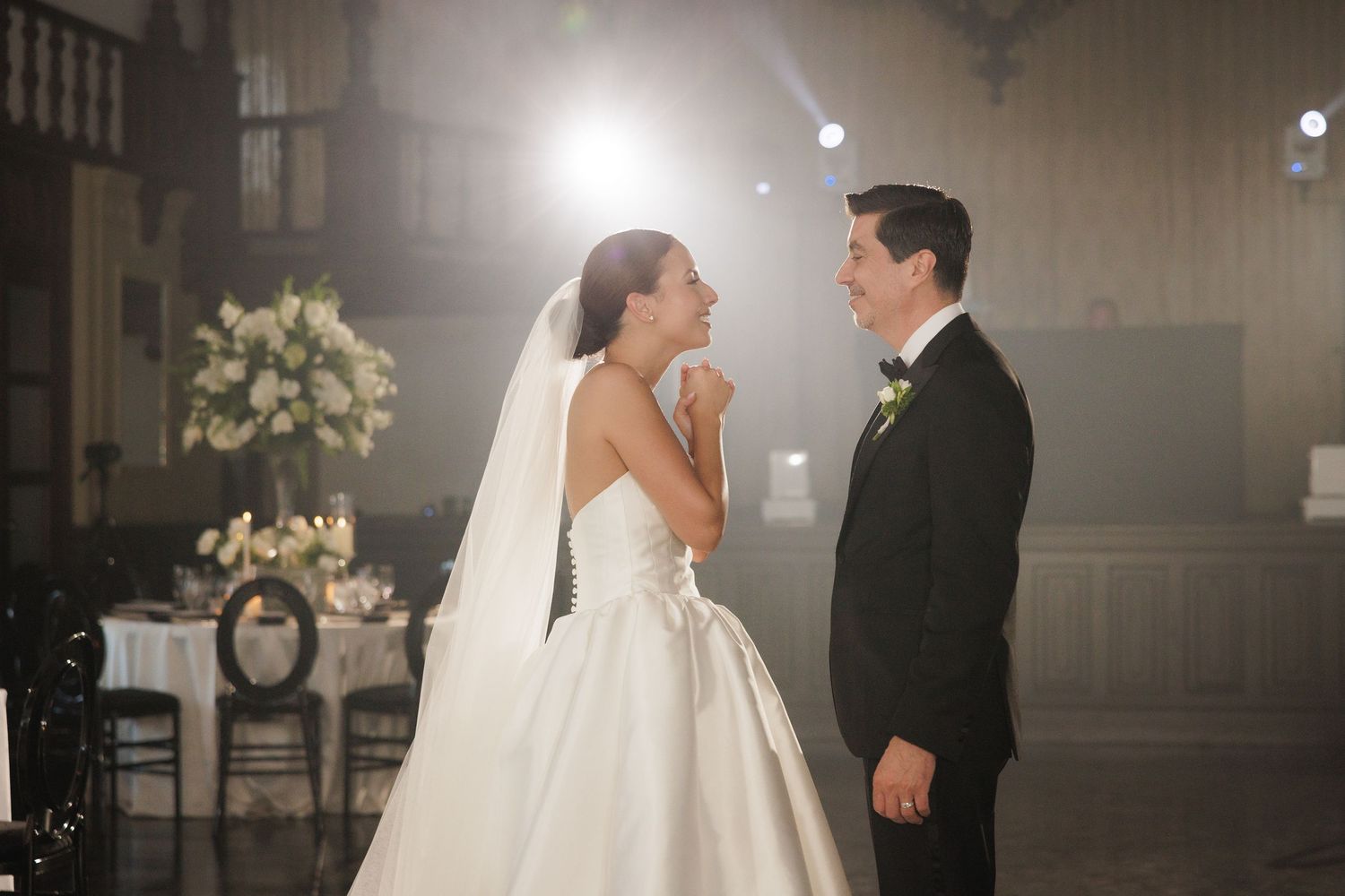 Romantic wedding couple shares intimate moments in a dimly lit church venue with elegant floral decorations.