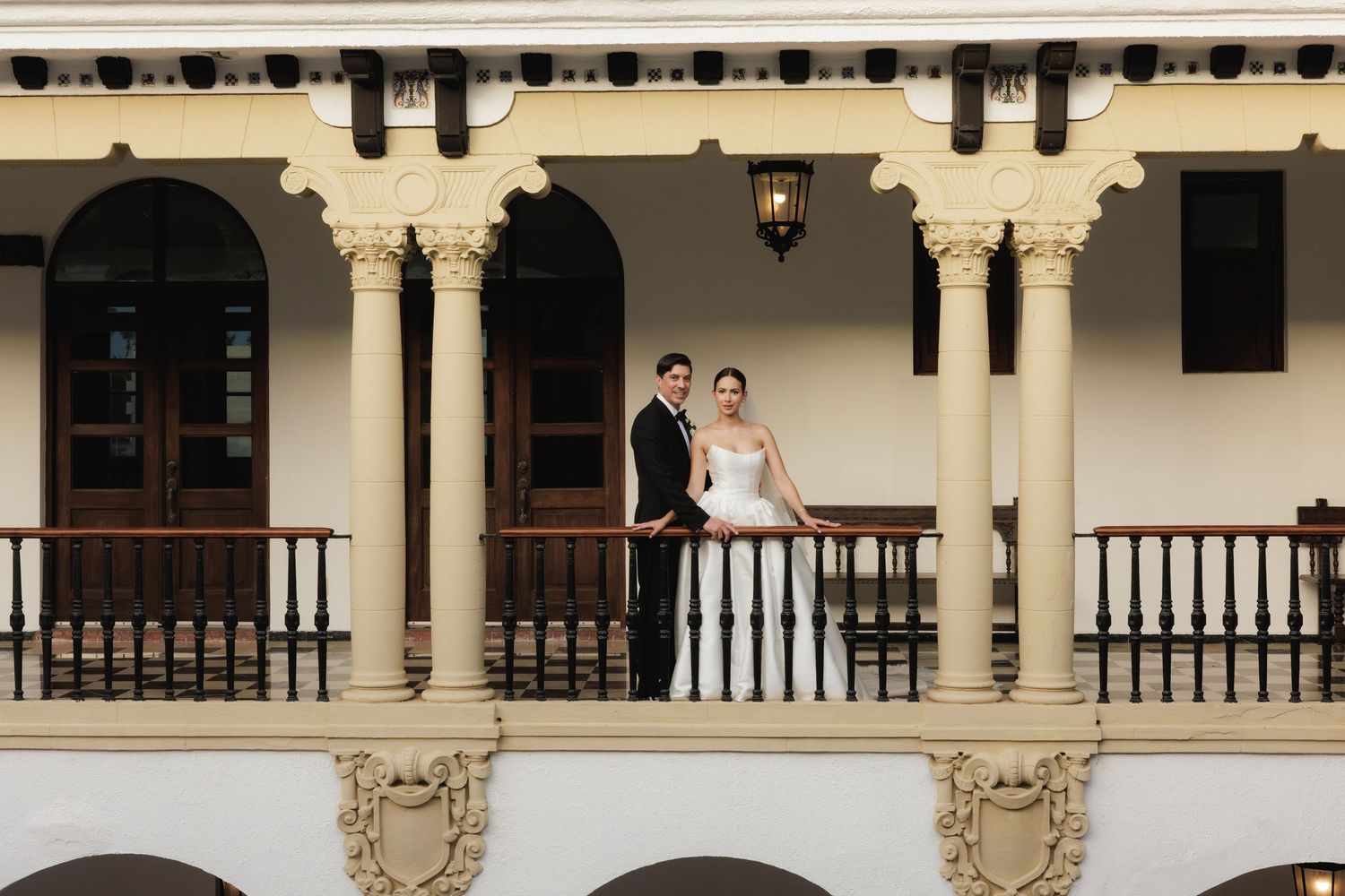 A panoramic view of a historic Spanish colonial style courtyard with white columns and wooden railings.