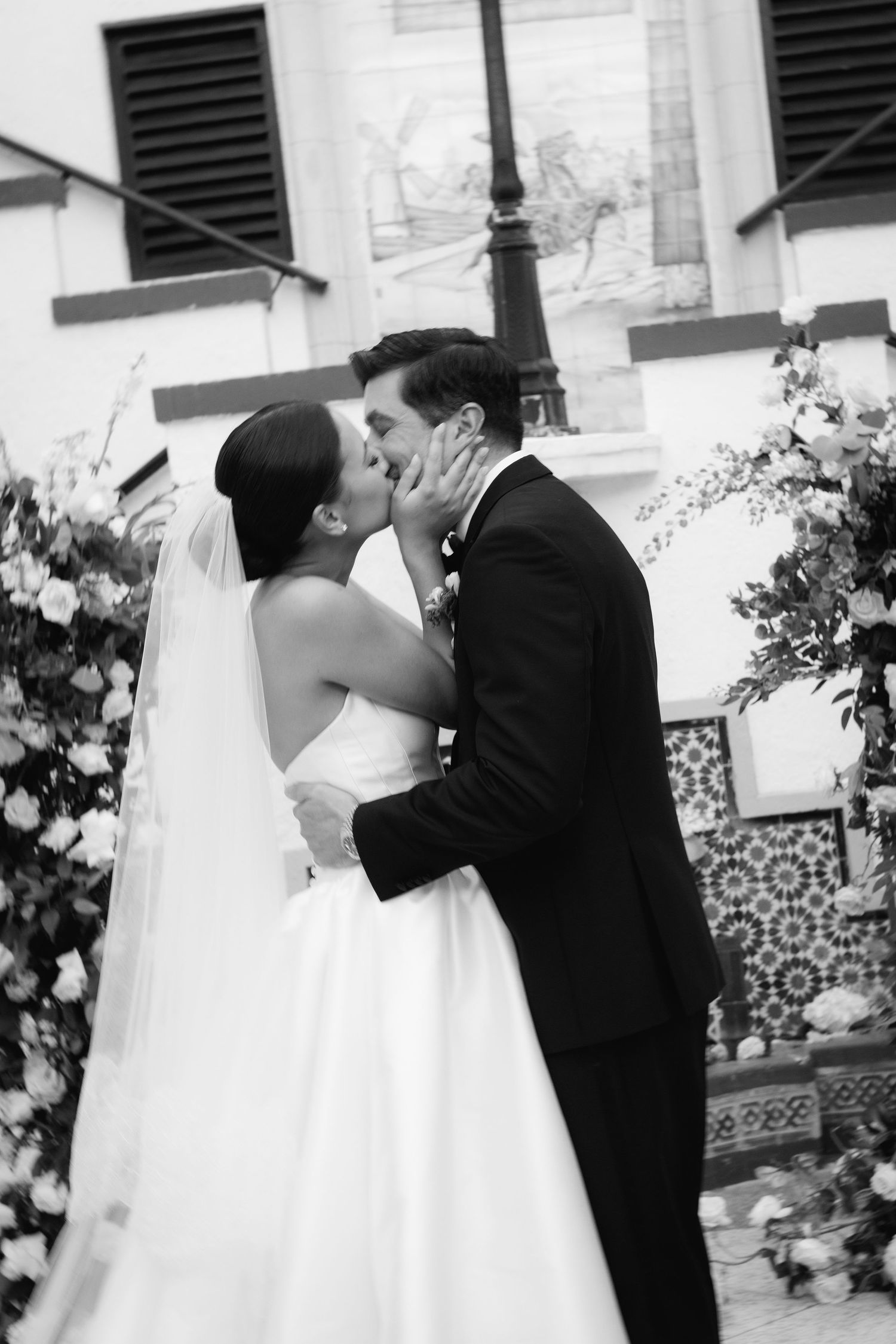 A romantic wedding moment captured in a series of black and white photos beside floral arrangements.