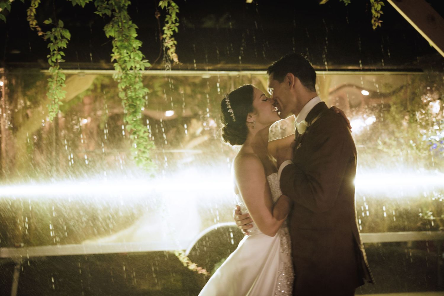 Elegant couple sharing a romantic moment under twinkling lights in a garden setting.