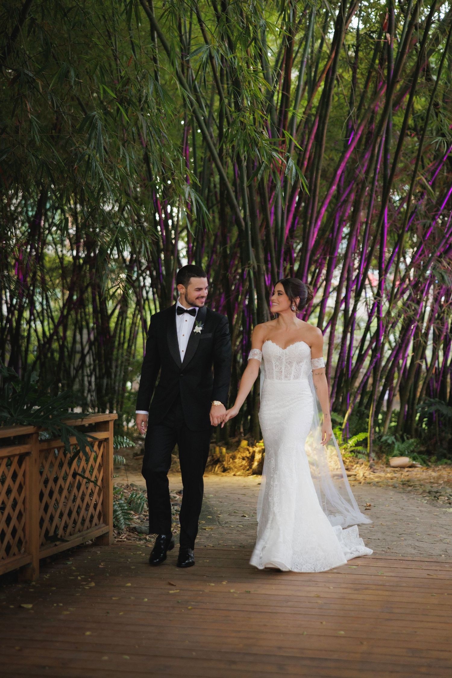 Couple poses on a wooden deck surrounded by lush bamboo garden during wedding portraits.