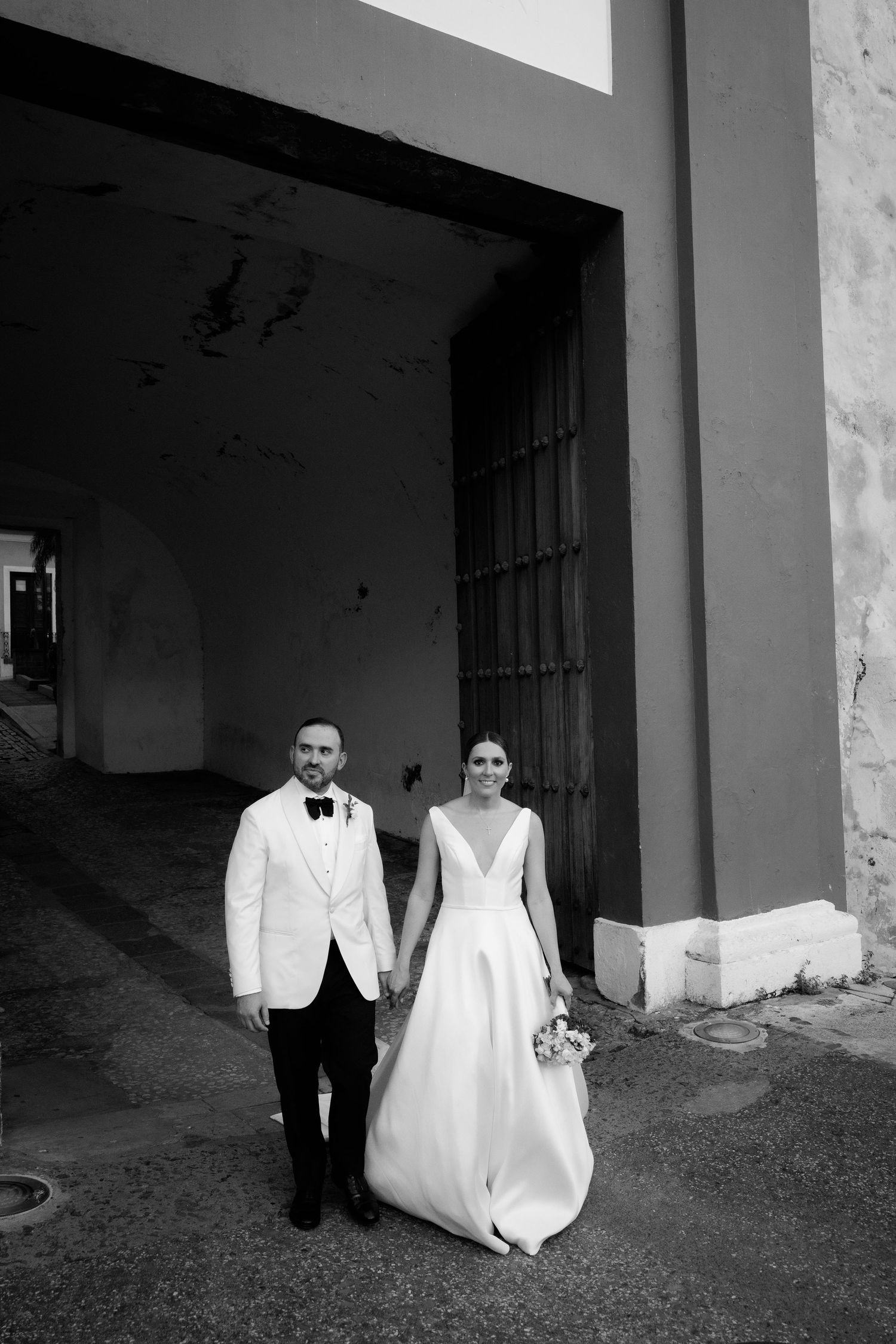 Wedding couple photographed in black and white against rustic stone architecture.