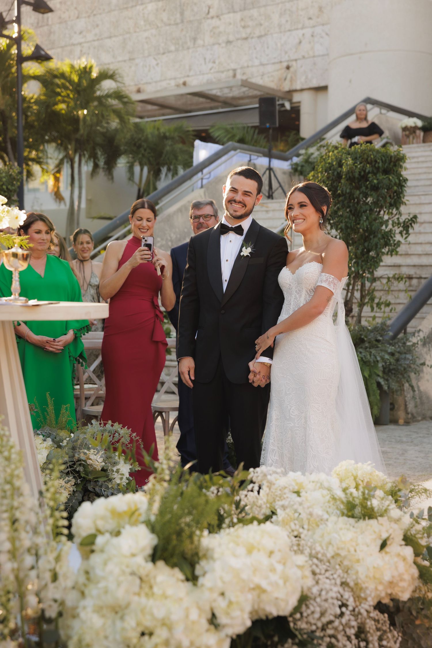 Elegant wedding ceremony setup with stone walls and cascading white floral arrangements.