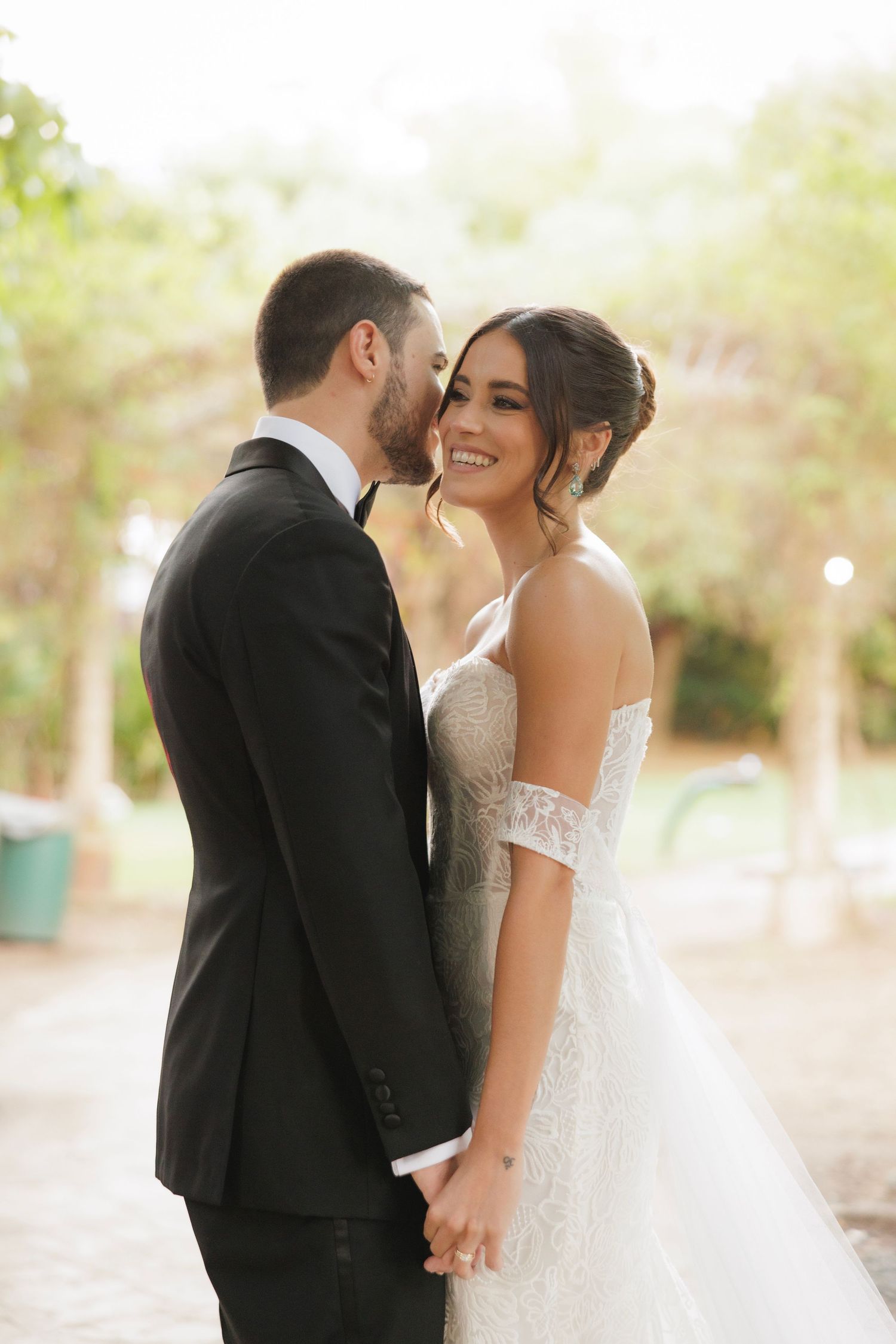 A romantic wedding portrait of a couple sharing an intimate moment in a sun-drenched outdoor setting.