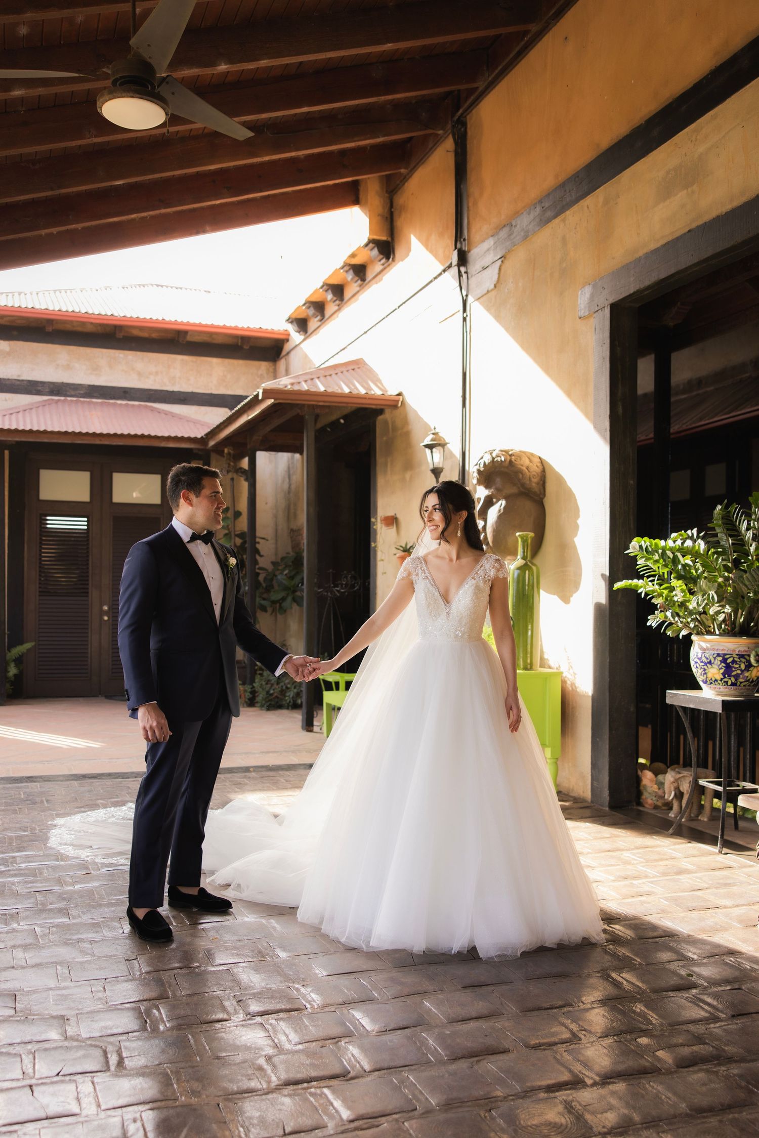 Bride and groom share a romantic first look moment under rustic archways with warm lighting.