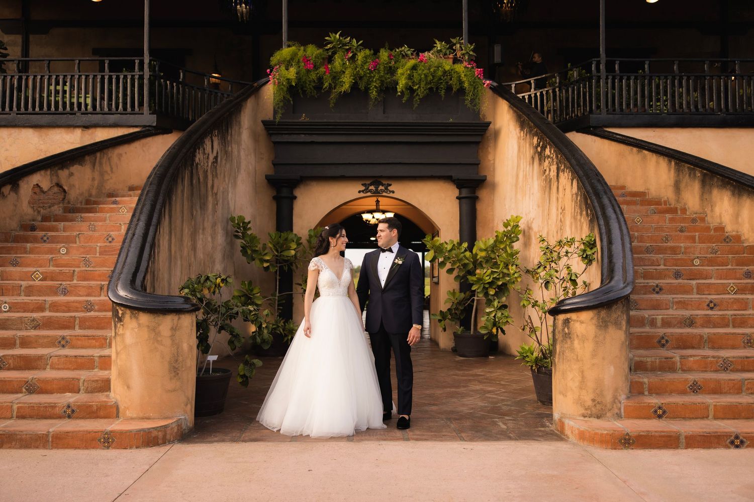 Wedding photography under brick archways with dramatic lighting and elegant architectural details.
