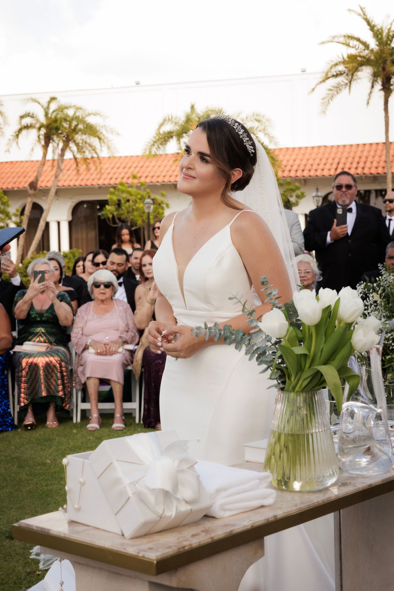 Four bridal snapshots at a wedding reception show celebrations with white decor and palm trees in an outdoor setting.