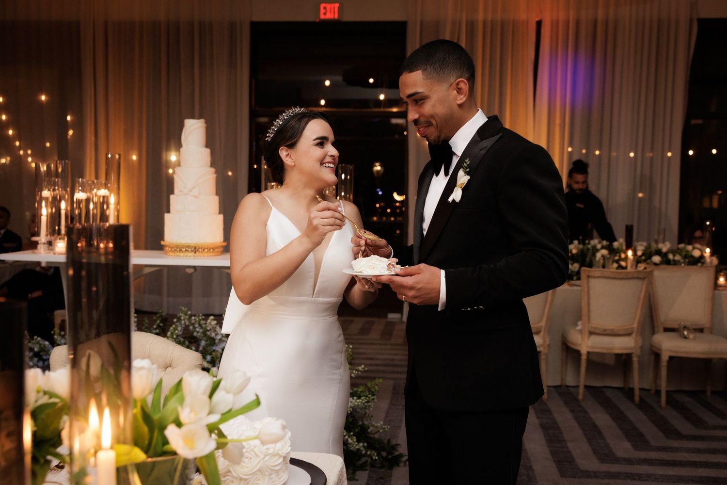 A joyful couple dances together during their wedding reception under warm lighting in an elegant ballroom.