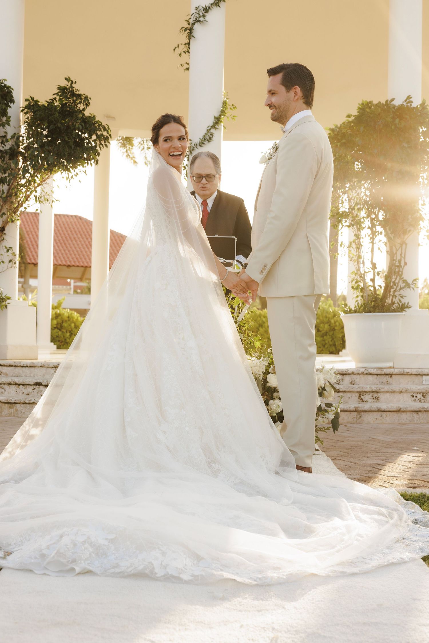 A series of romantic wedding photos showing a couple in white attire posing under pillars during golden hour.