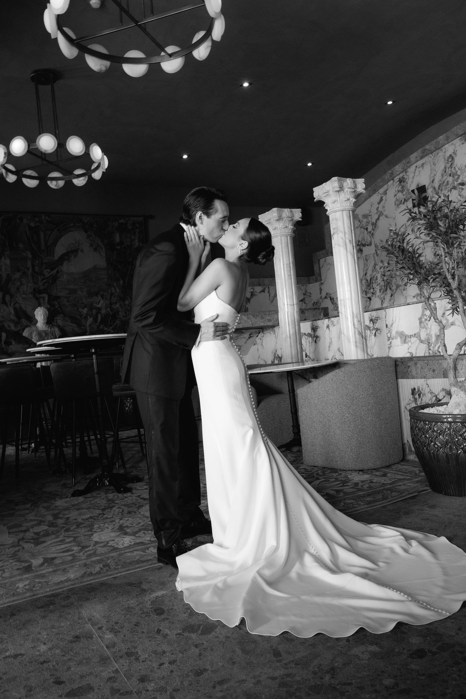 Black and white wedding photos capture intimate dance moments beneath ornate circular chandeliers.