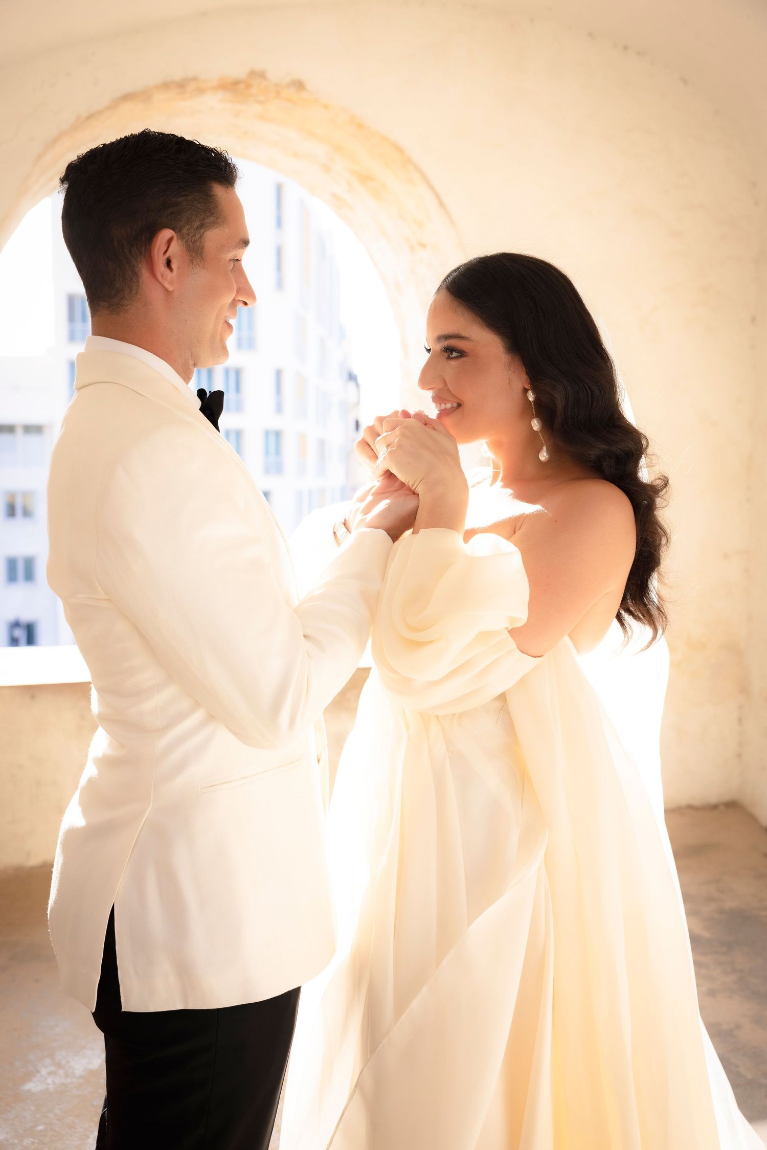 Romantic wedding portraits bathed in soft natural light against cream colored walls.