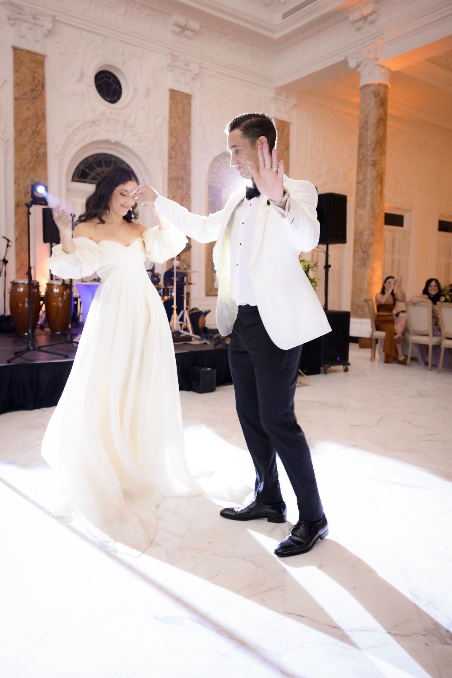 Wedding couple performing choreographed dance moves in elegant ballroom setting.