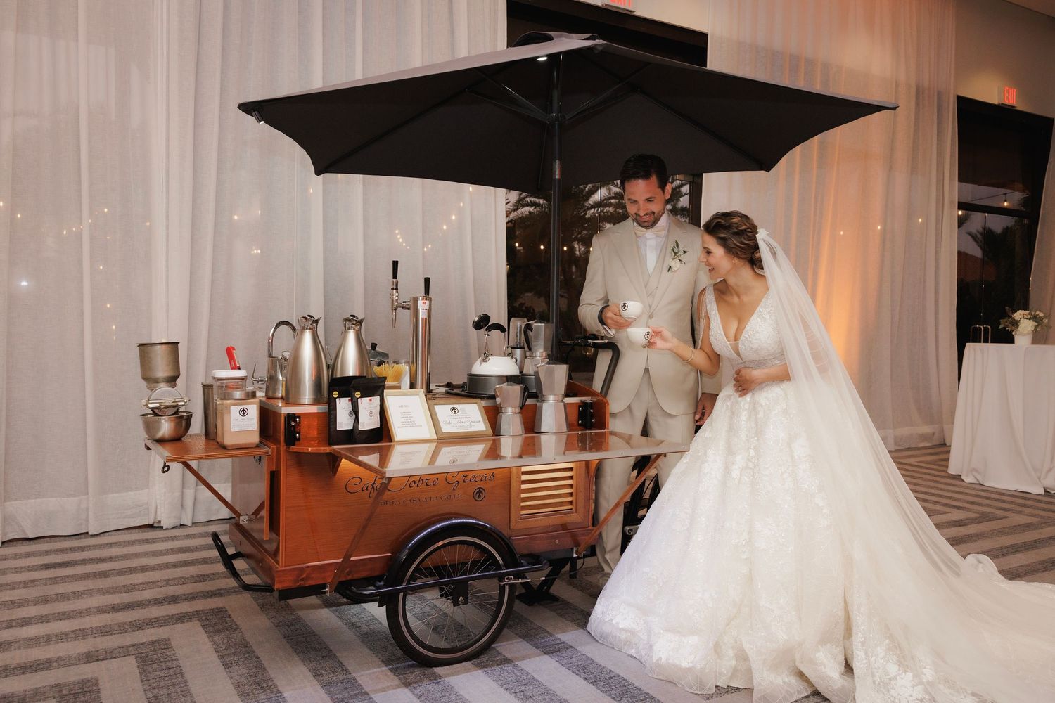 A couple in wedding attire poses with an umbrella during their romantic indoor photo session.