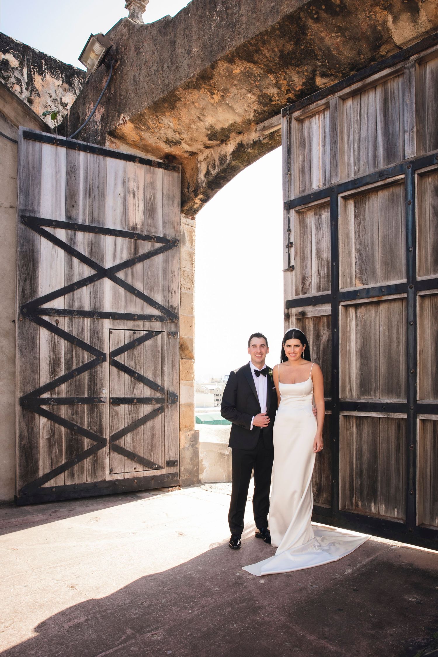 Wedding photo series showing couple posed in rustic wooden doorways of historic fortress structure.