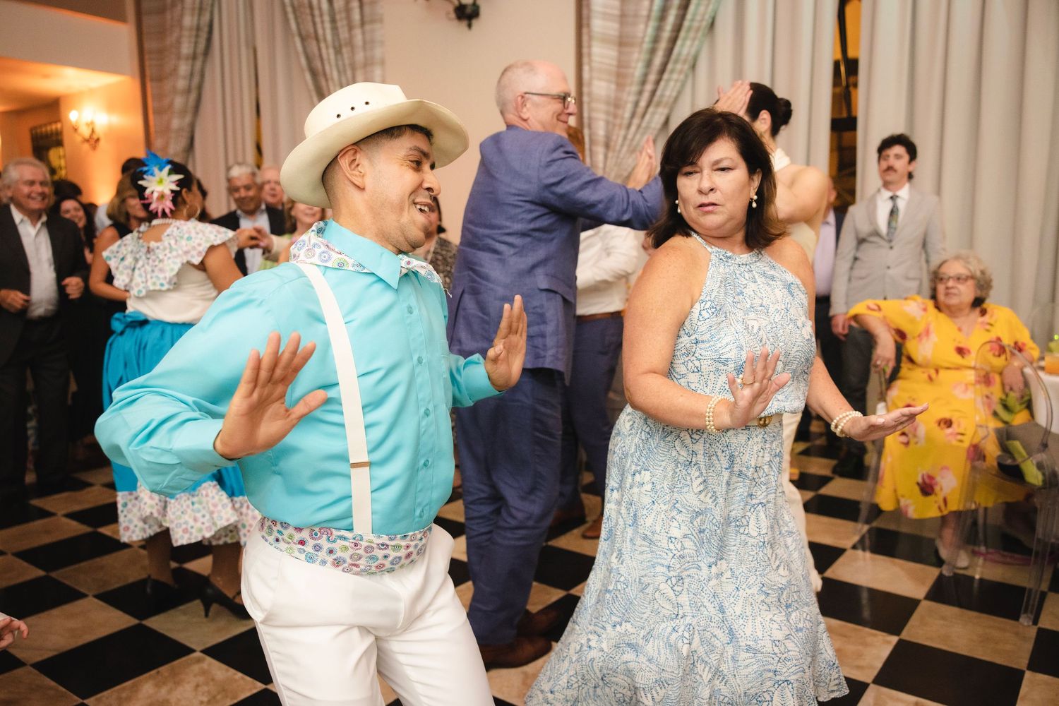 Couples dance together on a black and white checkered dance floor at an elegant social event.
