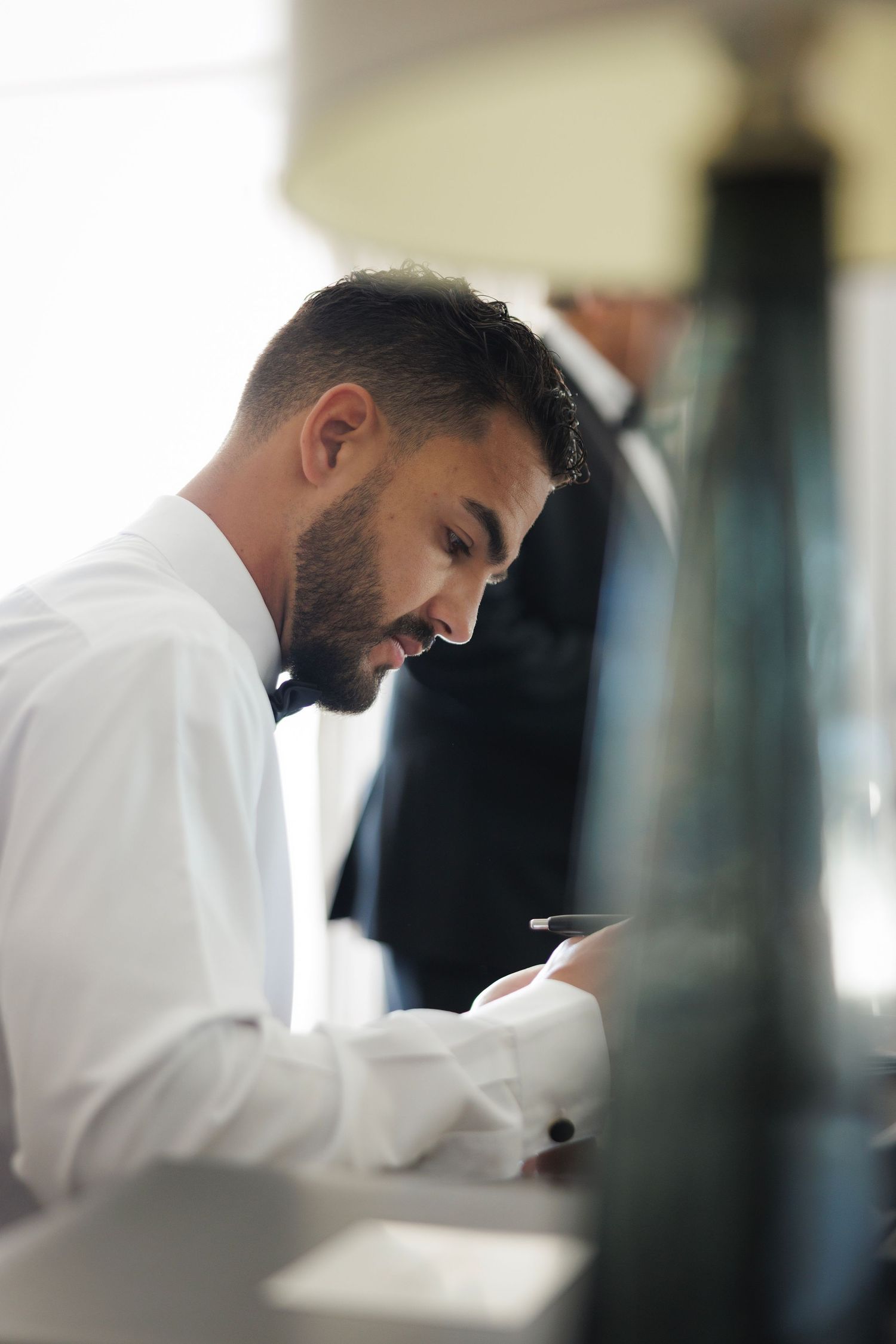 Side profile of someone in white dress shirt looking down while working at desk in professional setting.
