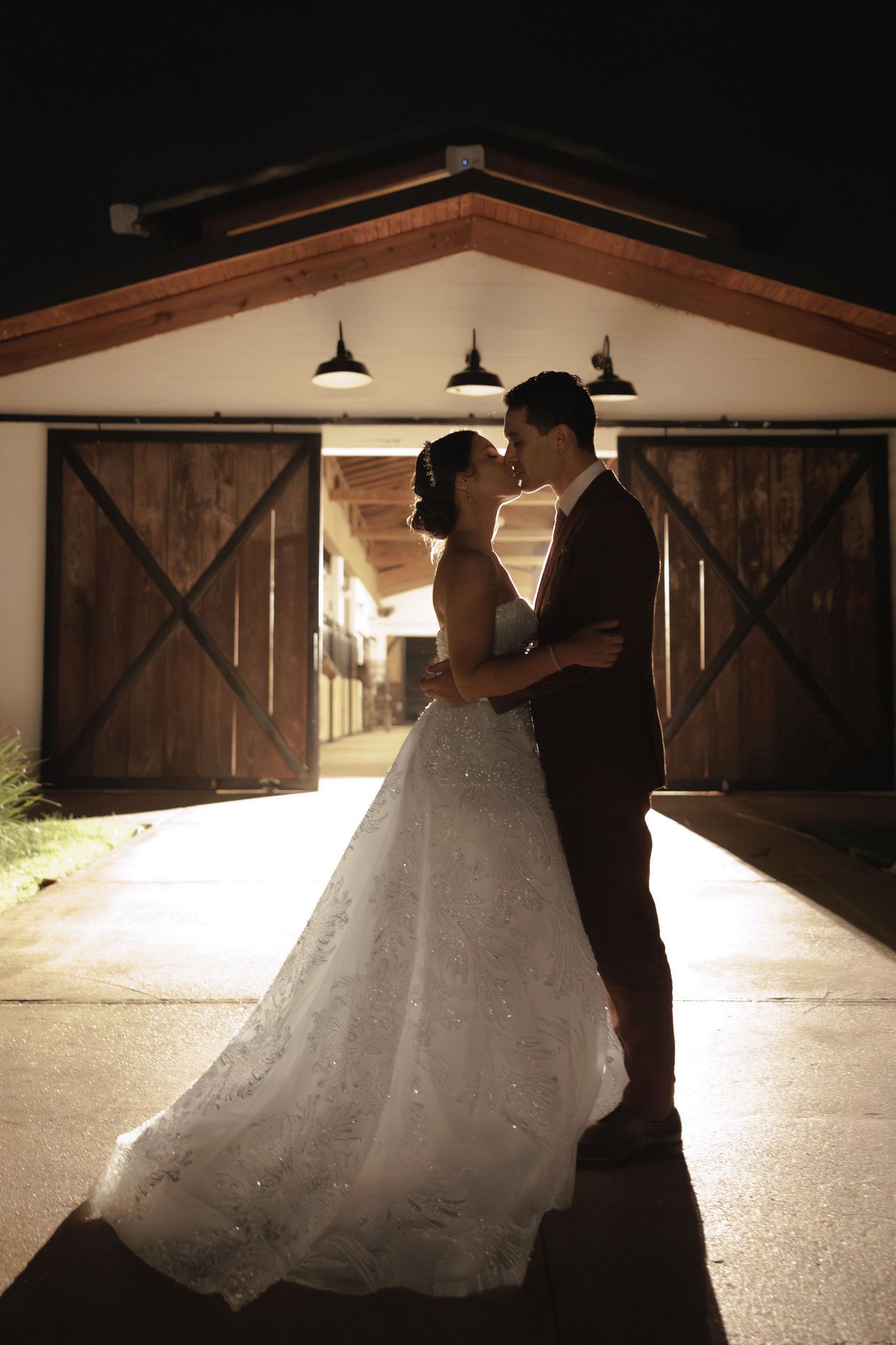 A couple dances in front of a rustic barn with dramatic nighttime lighting.