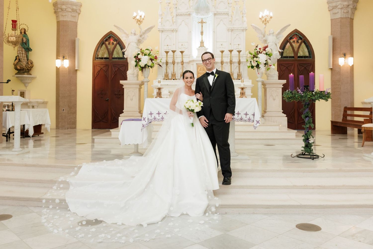 Elegant wedding ceremony in a beautiful church sanctuary decorated with white floral arrangements.